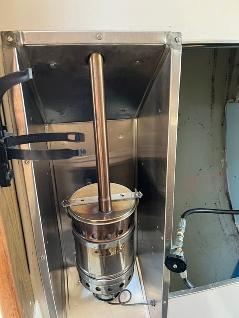 A metal stove inside a boat, surrounded by a protective casing.
