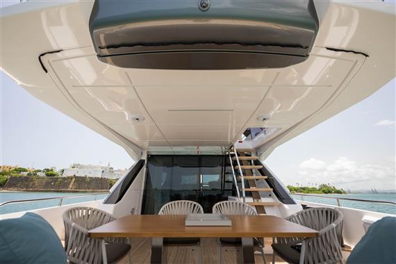 2023 Ferretti Yachts 720 deck with dining area and stairs, overlooking the sea.