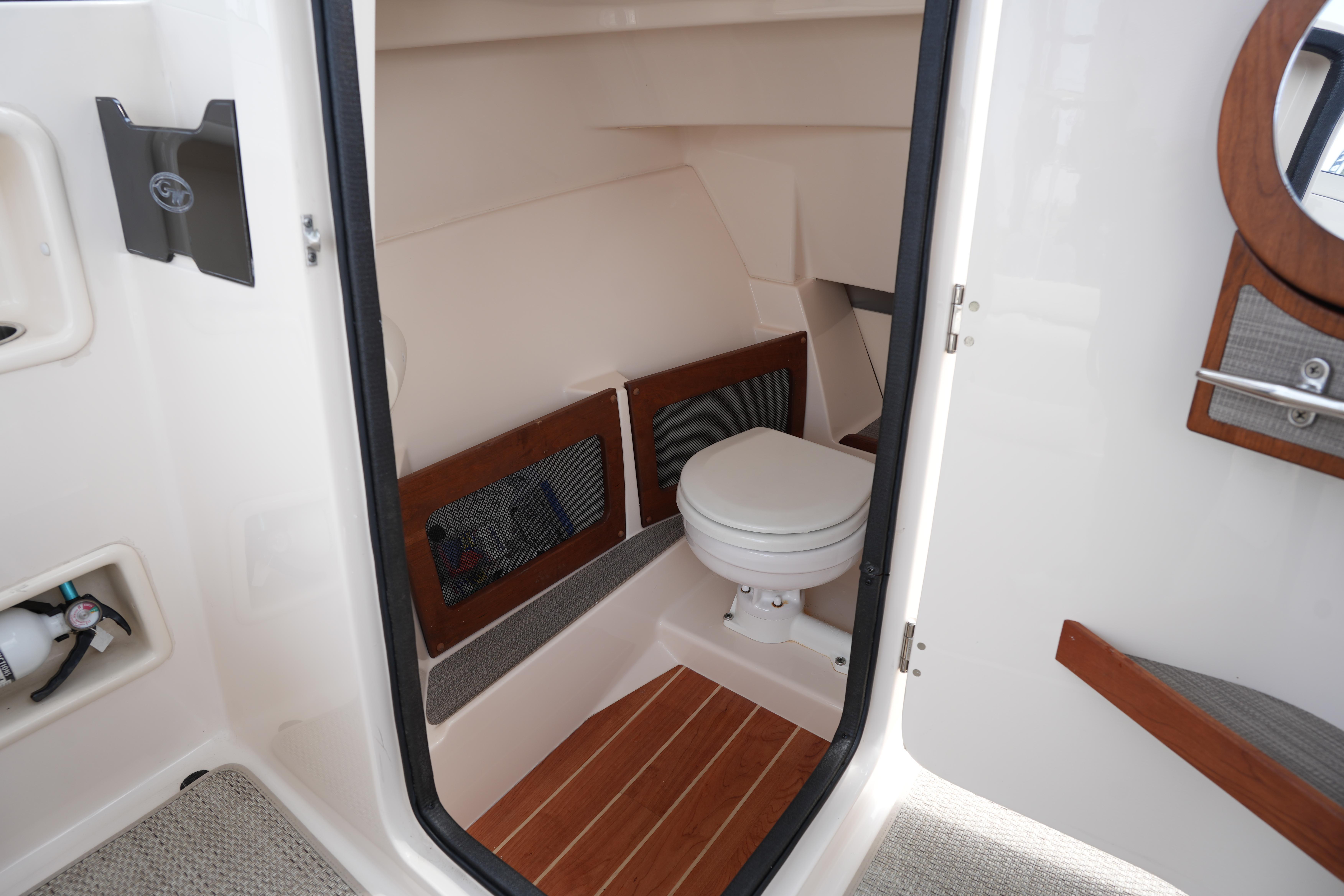 Interior view of 2021 Grady-White Freedom 235 boat's compact bathroom with toilet.