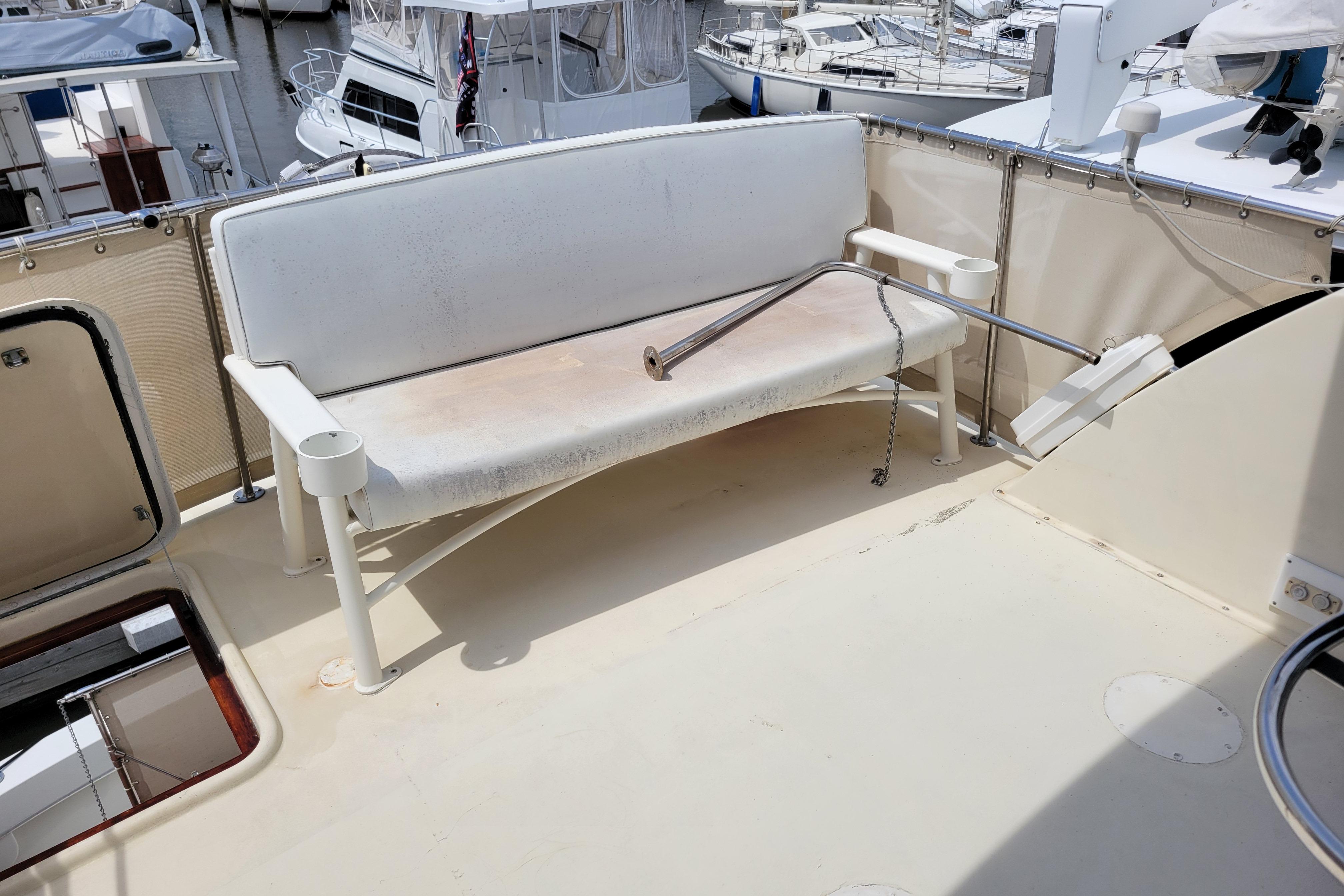 1980 Hatteras 53 Yacht Fisherman deck with white bench and railing, docked at marina.