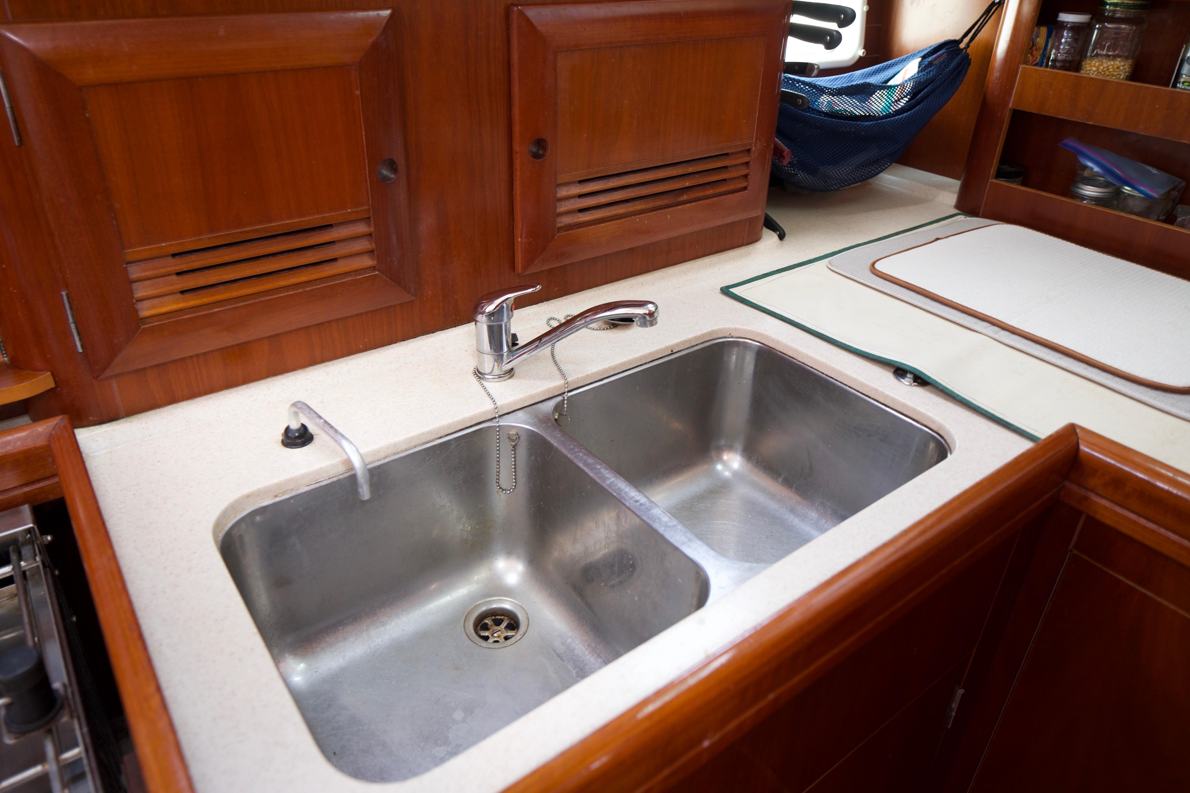Galley sink in 2005 Beneteau 423 yacht, featuring dual basins and wooden cabinetry.