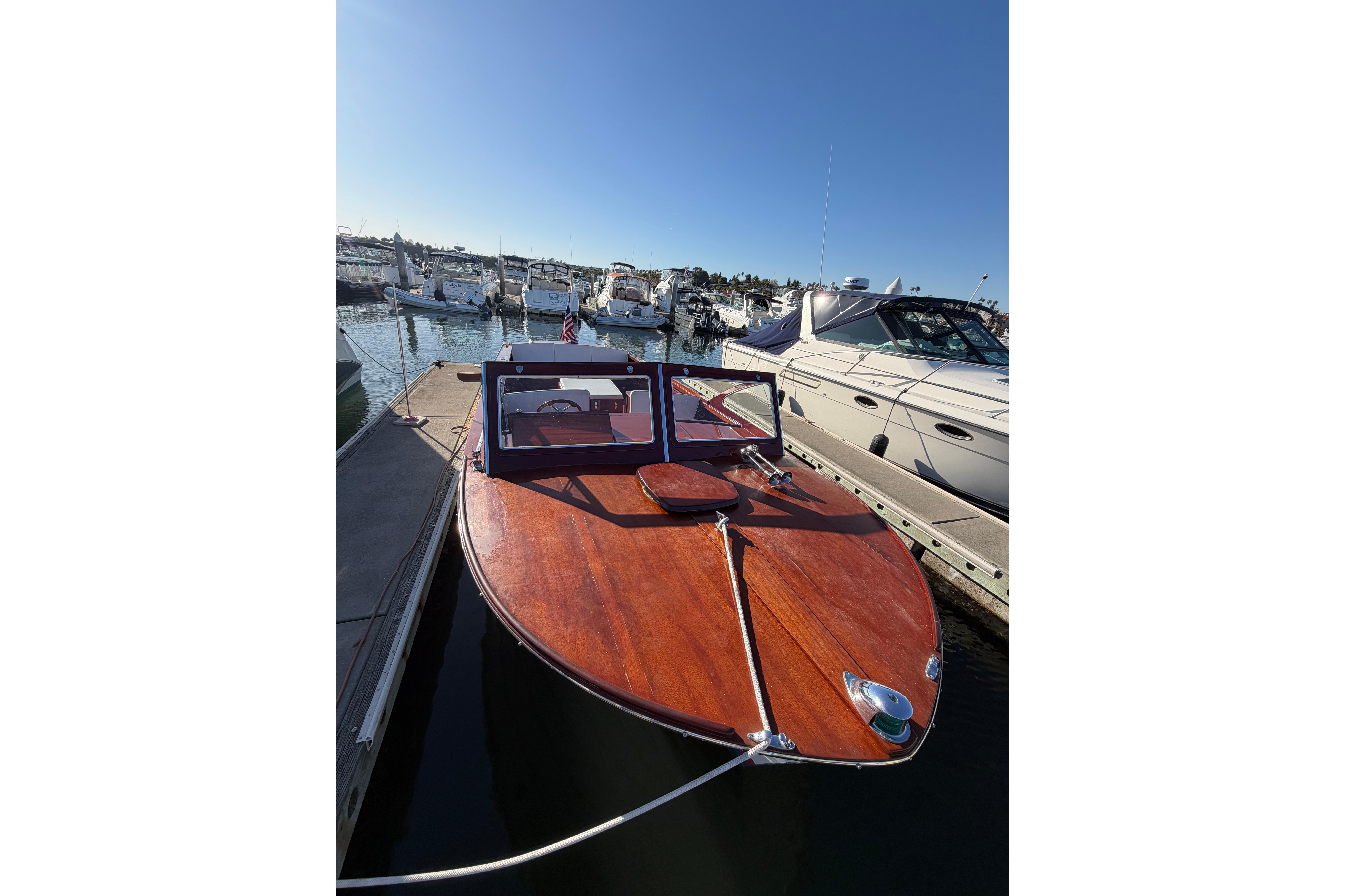 1964 Lyman 25 Sleeper boat docked at a marina under clear blue skies.