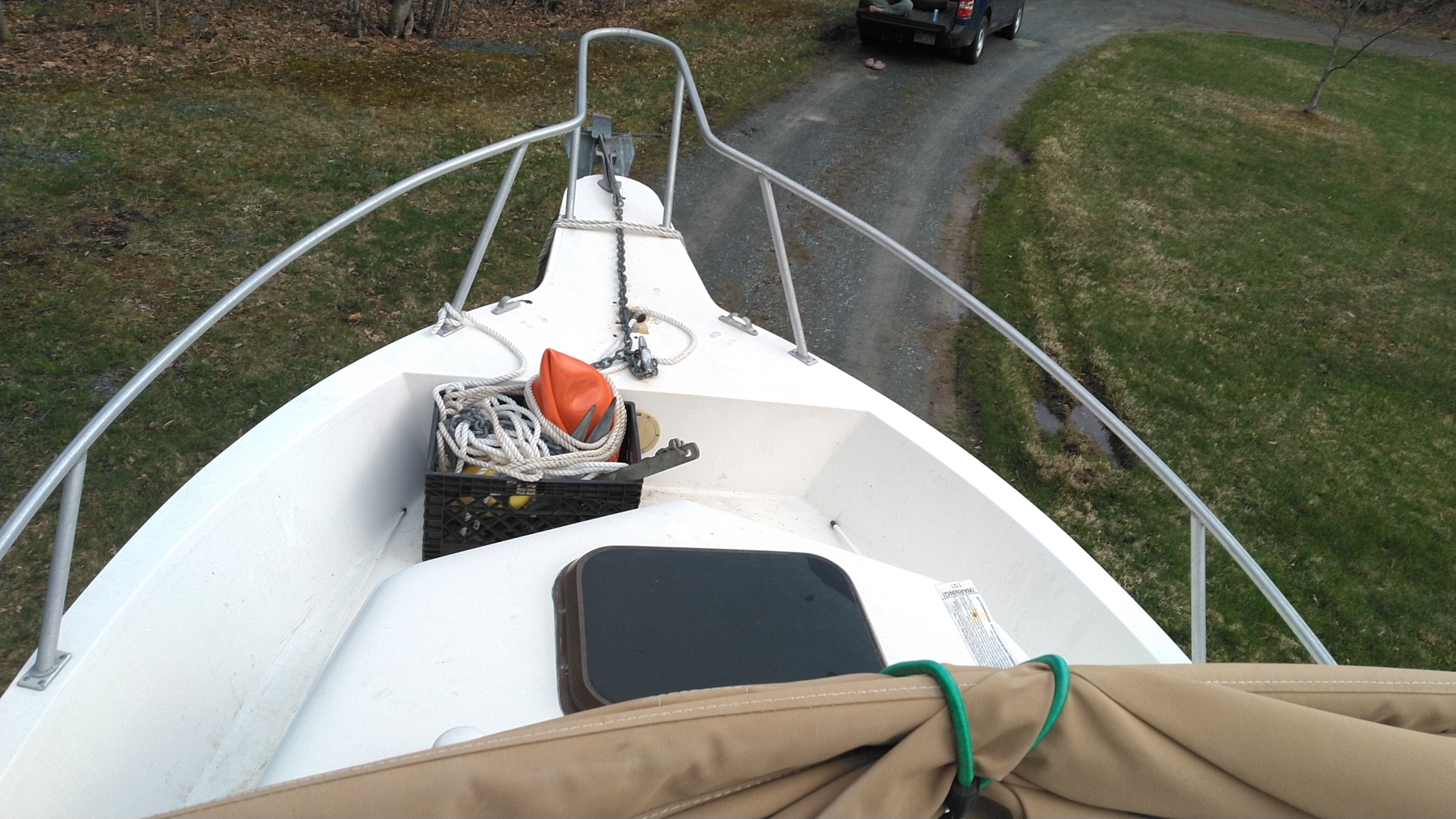 A boat on a trailer with ropes and an orange buoy on deck.