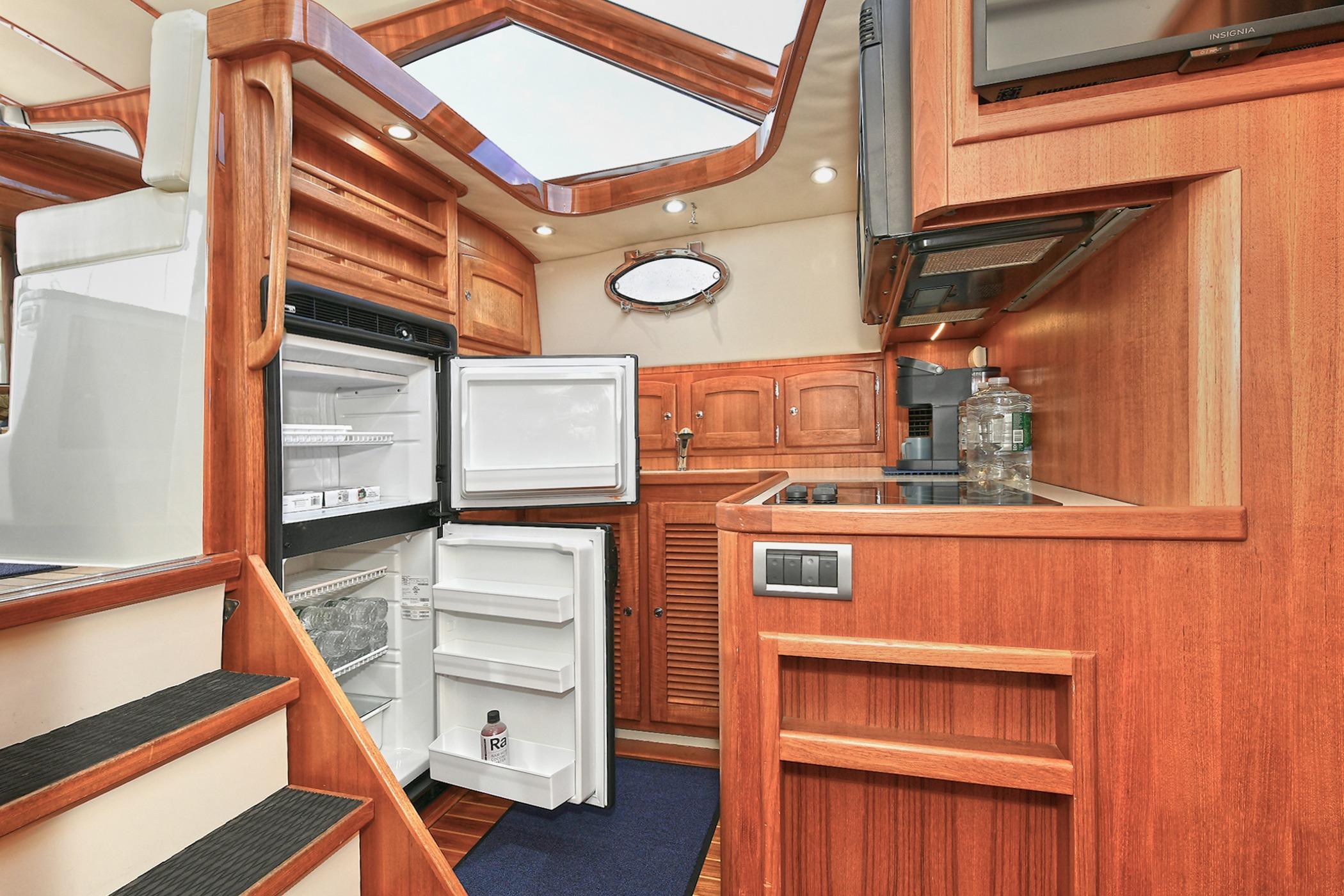 Luxurious 2005 San Juan Downeast Express yacht interior with open fridge and wooden cabinetry.