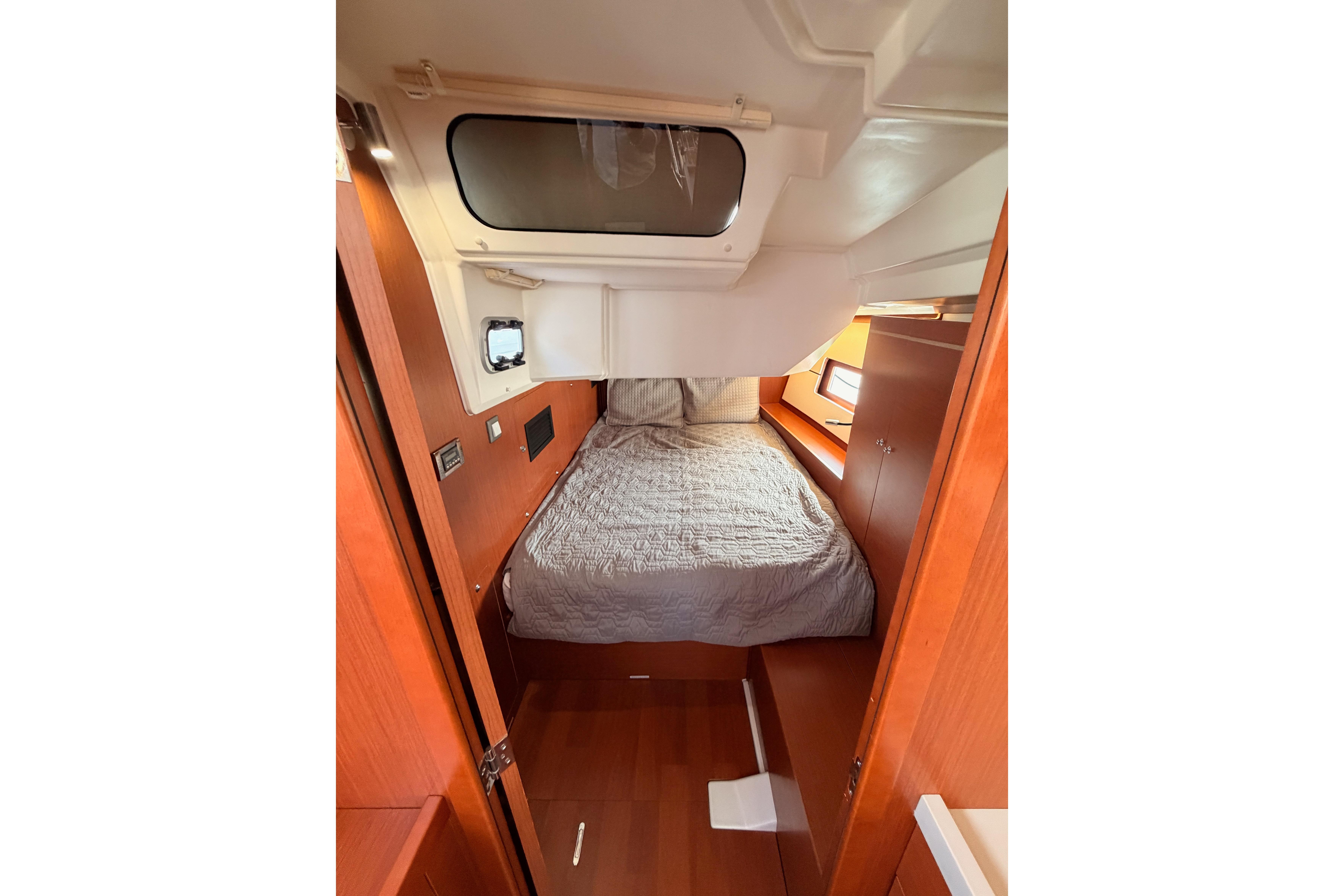 Interior cabin of 2020 Beneteau Oceanis 46.1 yacht with cozy bed and wooden finish.
