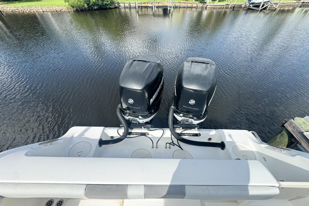 2018 Mako 284 Center Console boat with dual outboard motors on a calm waterway.
