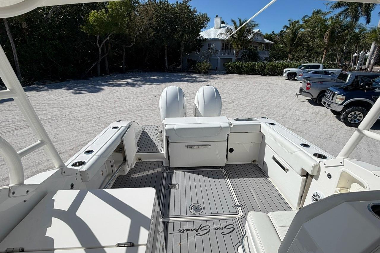2021 Pursuit DC 266 Dual Console boat interior with seating and storage, parked on sandy lot.