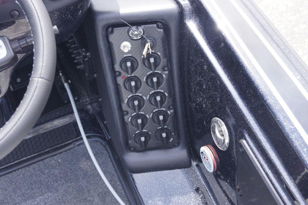 Control panel of a 2026 Phoenix 721 ZXL boat with multiple switches and steering wheel.