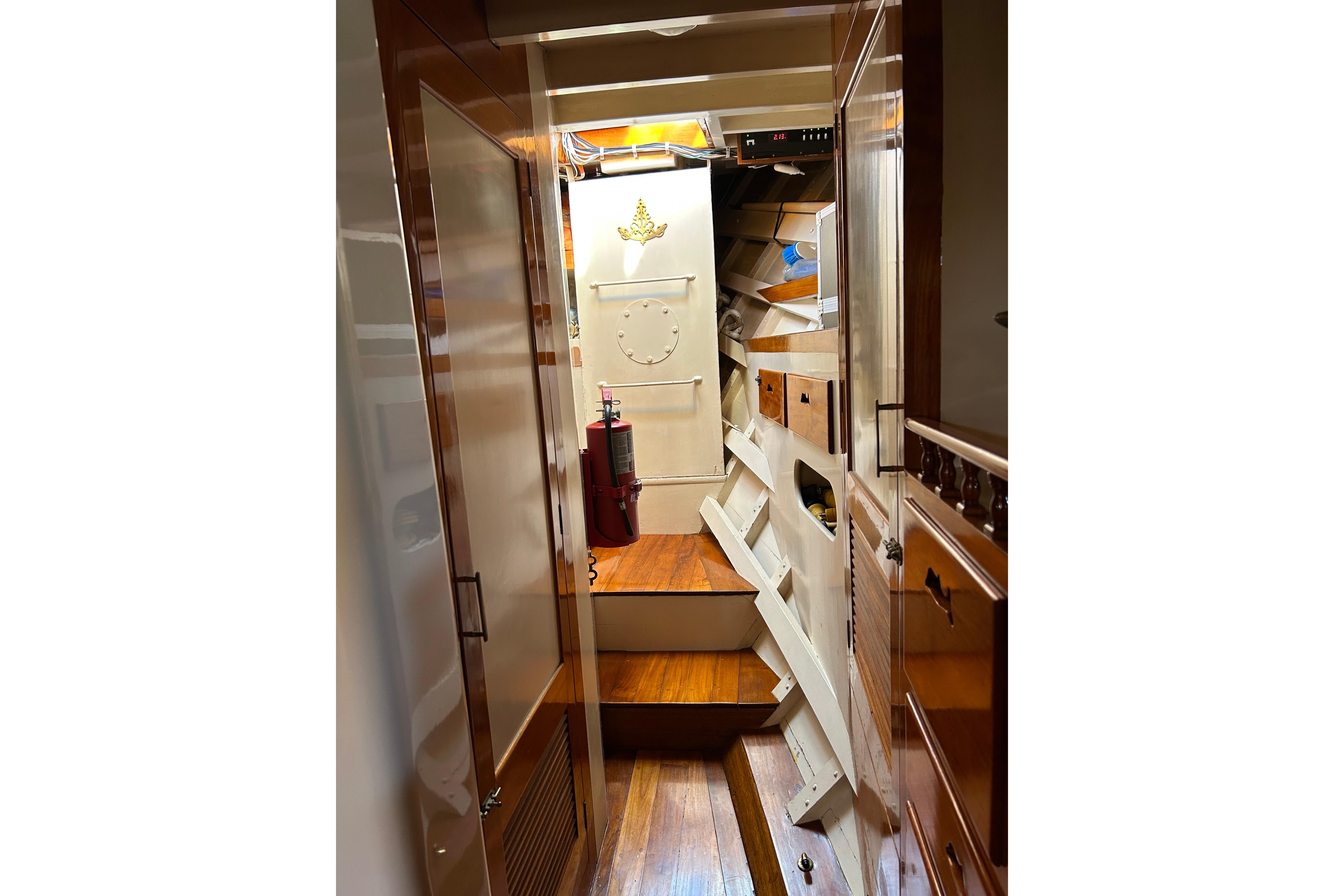 Narrow wooden hallway inside 1975 Robin Fong PORPOISE boat, featuring storage and fire extinguisher.