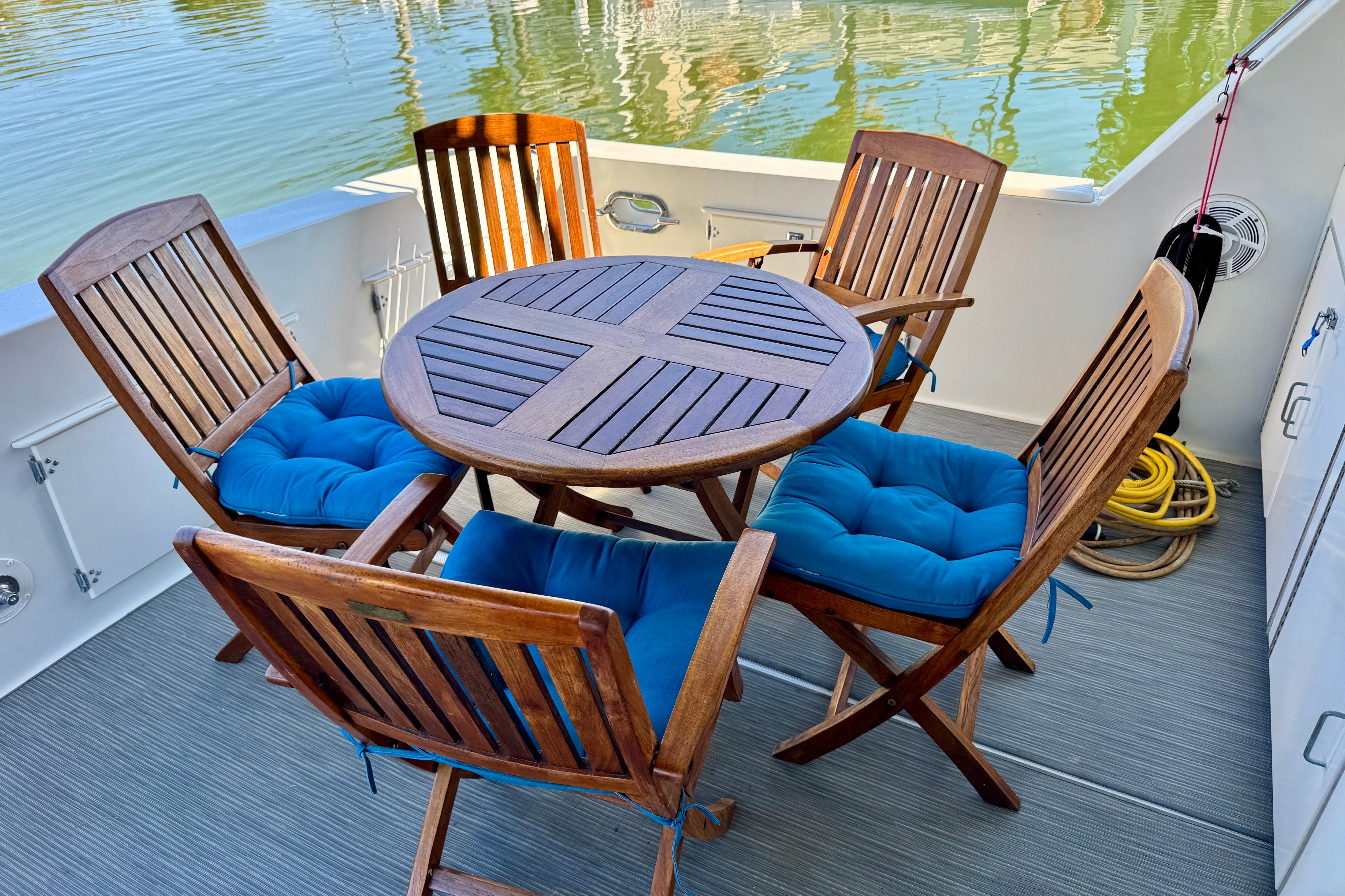 Outdoor seating area on 1993 Tollycraft 57 Pilothouse Motor Yacht with wooden chairs and blue cushions.