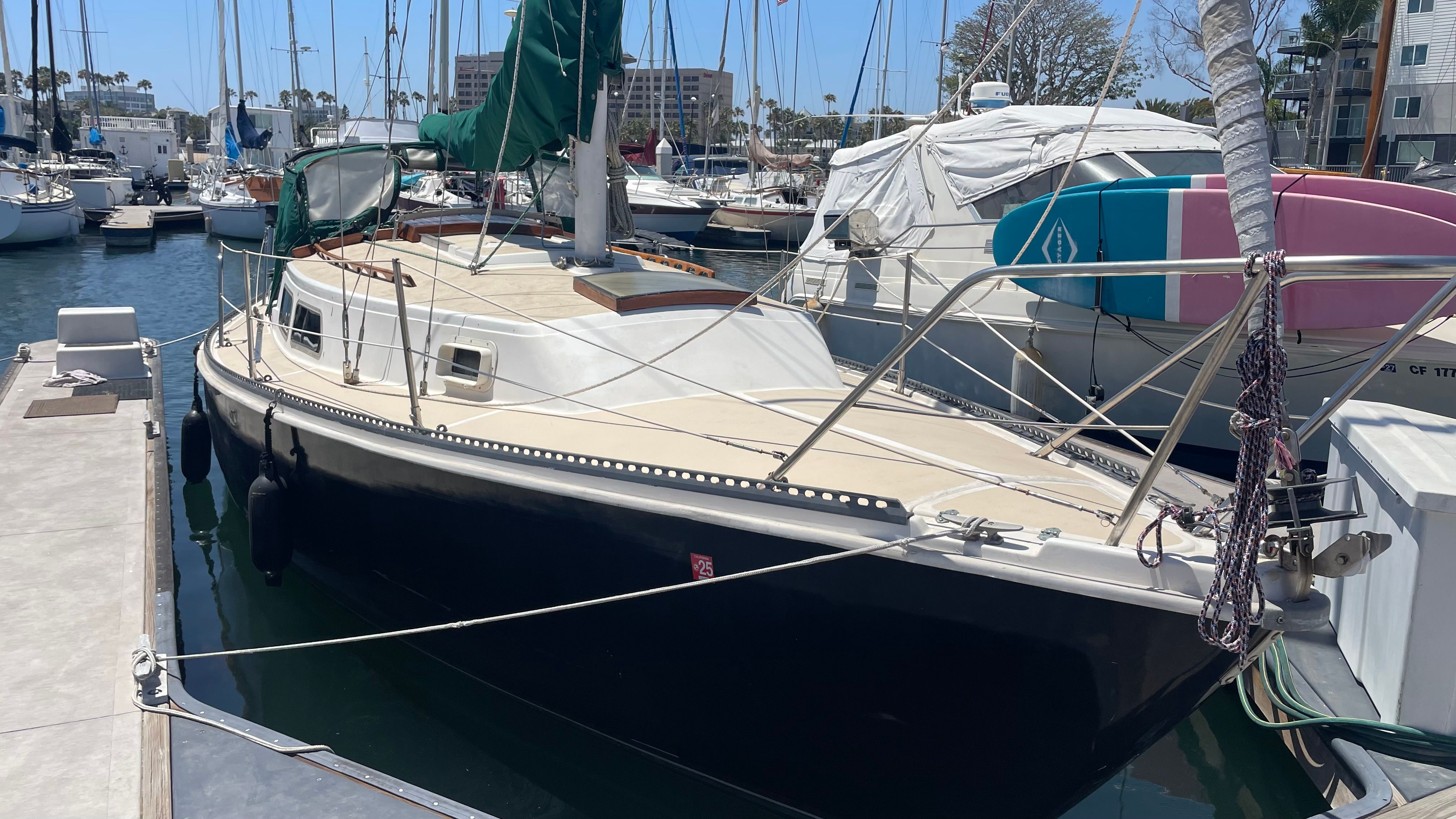 A 1980 Newport 30 sailboat docked in a marina. It features a black hull design and green sail.