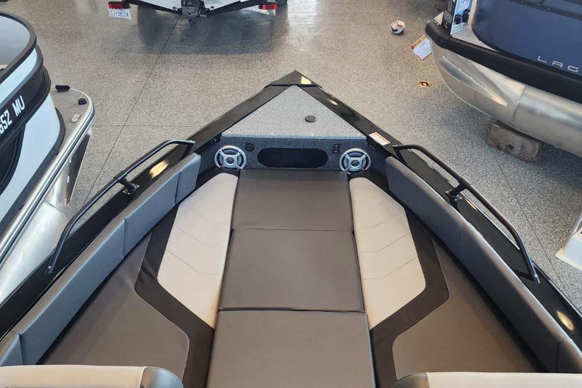 2023 Lowe boat interior with cushioned seating and speakers, displayed in a showroom.