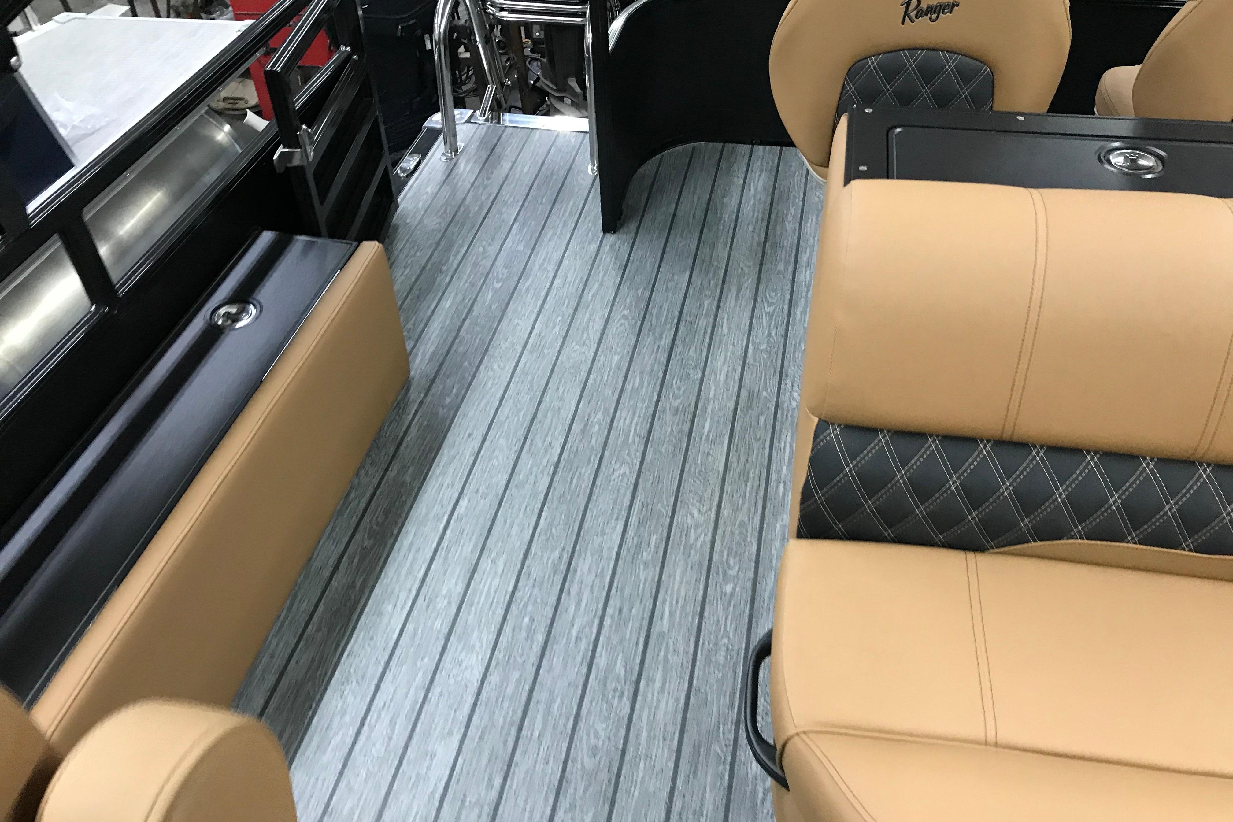 2026 Ranger Reata 220FC interior with tan seating and wood-style flooring.