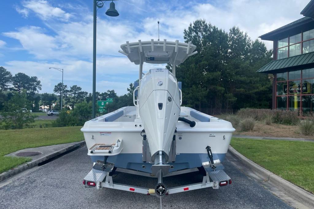 2025 Ranger 2360 Bay boat on trailer, parked outdoors near greenery and building.