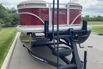 2024 Sun Tracker Party Barge 22 DLX pontoon boat on trailer, parked outdoors.