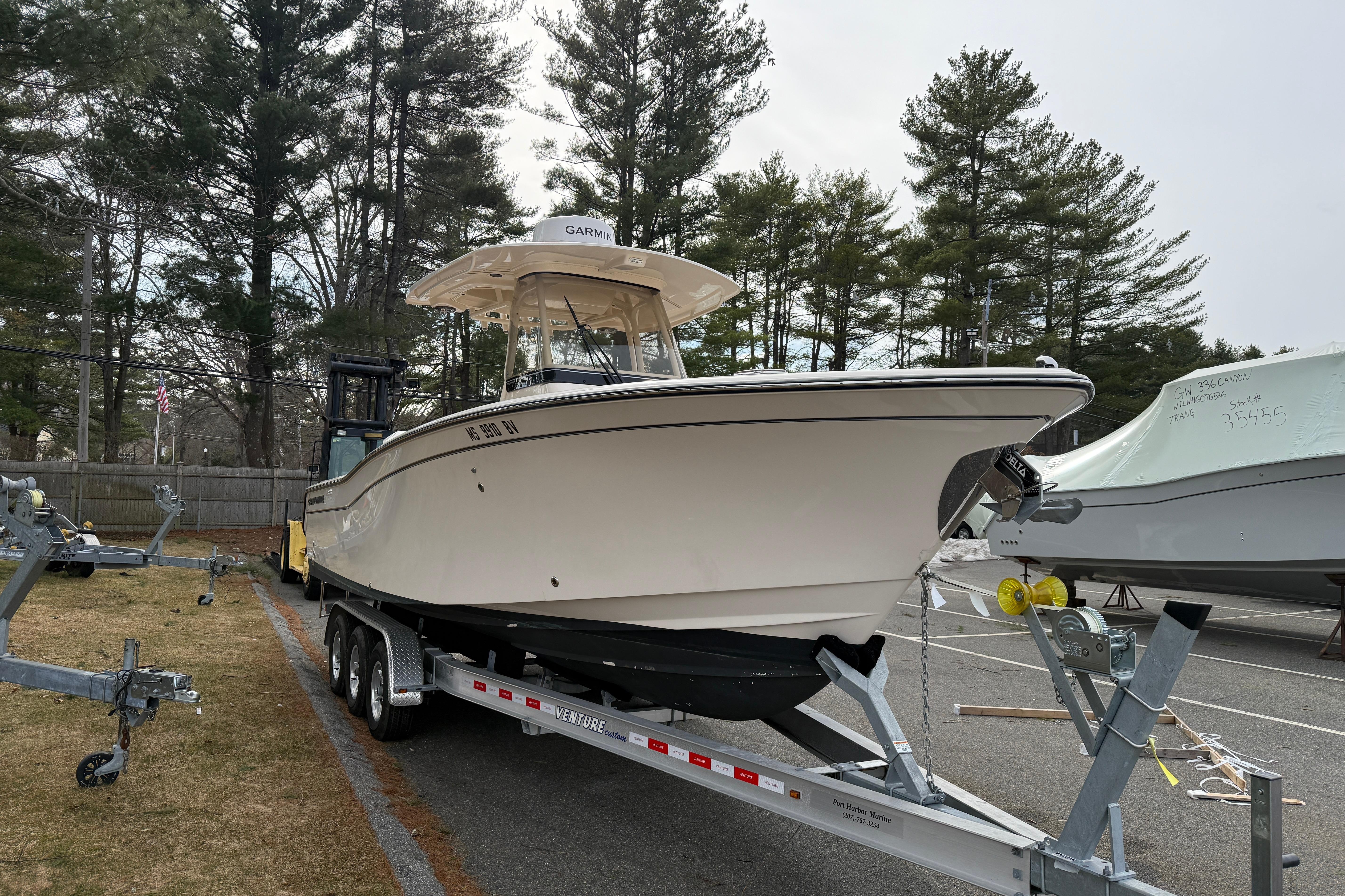 2024 Grady-White Canyon 271 boat on trailer in parking lot, surrounded by trees.