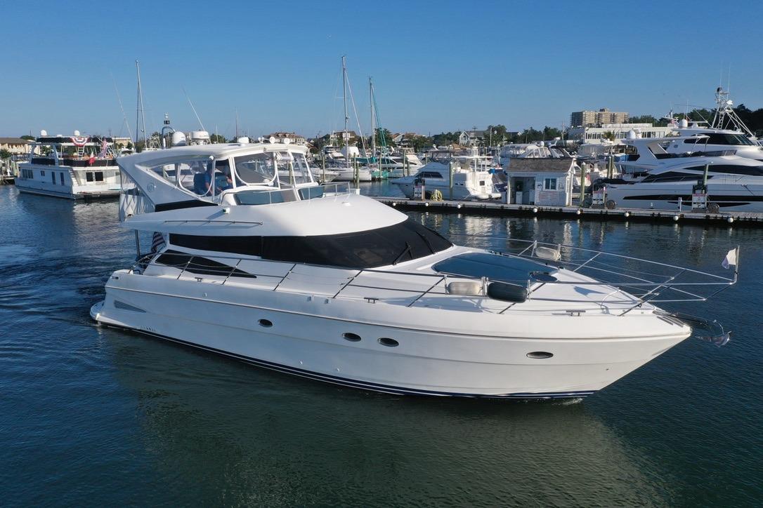 2005 Neptunus 56 Flybridge yacht cruising in a marina, surrounded by other boats.