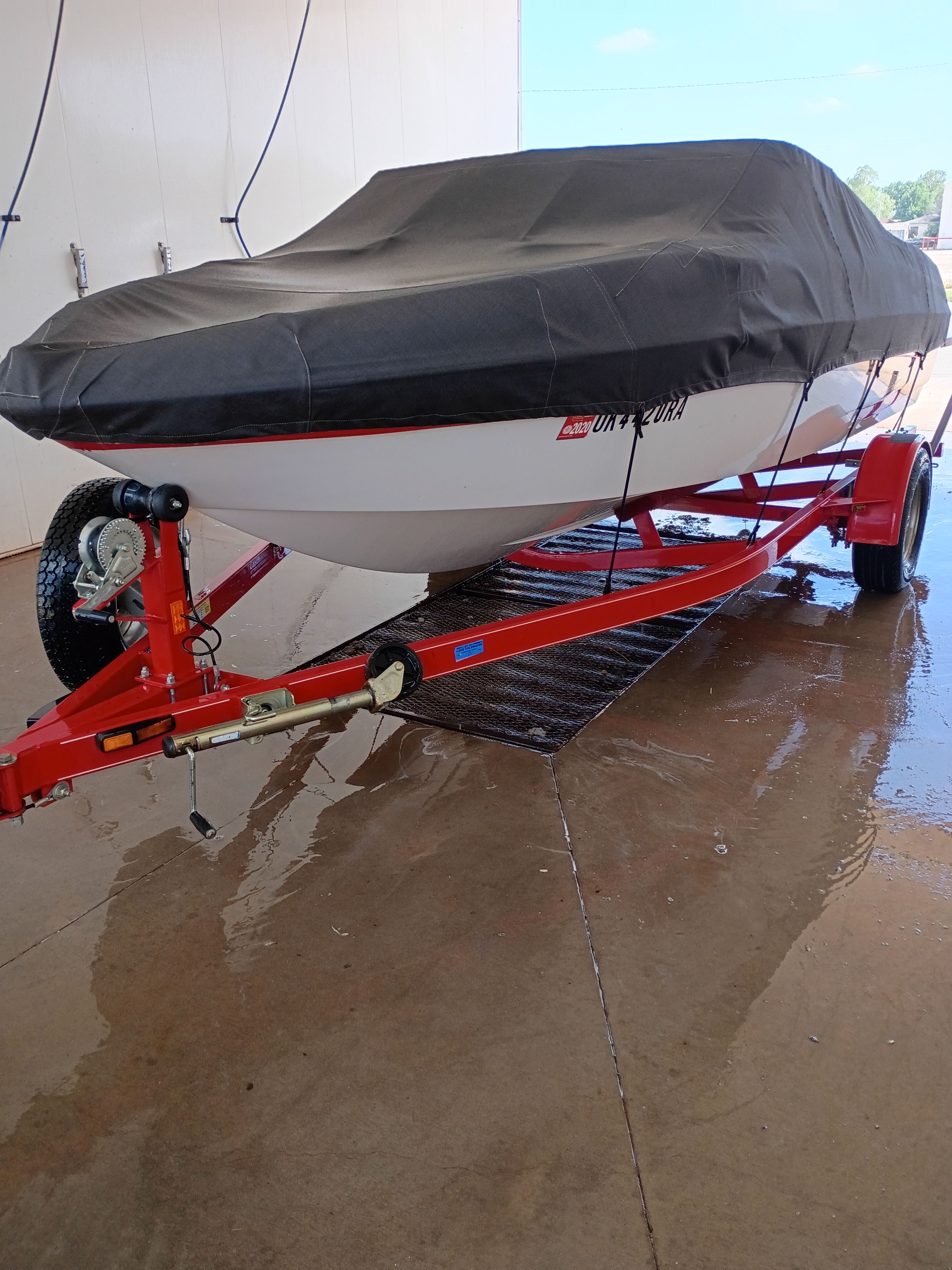 2010 Glastron MX 185 boat on red trailer, covered.