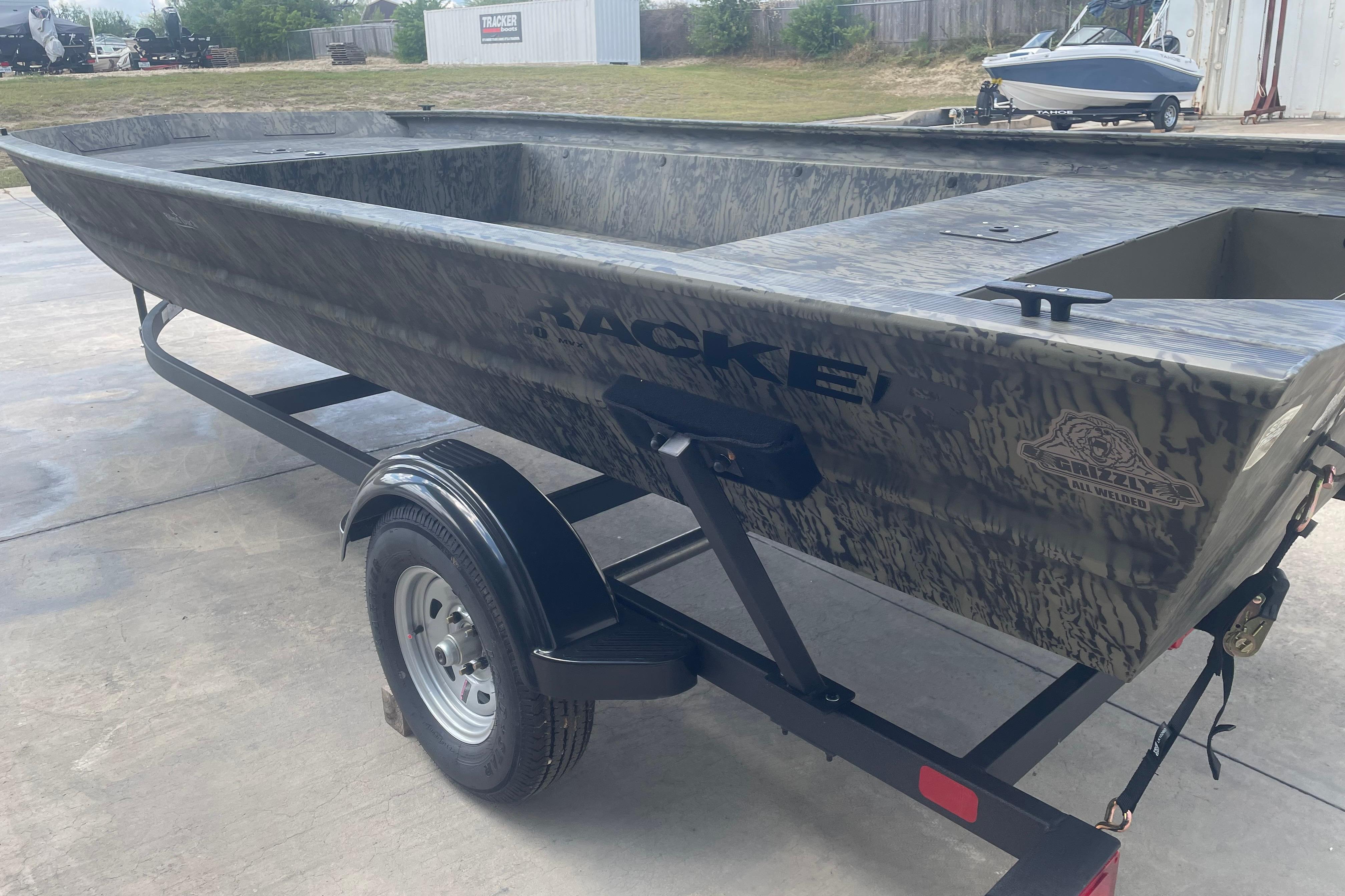 2026 Tracker Grizzly 1860 Utility boat on trailer, camo design, parked outdoors.