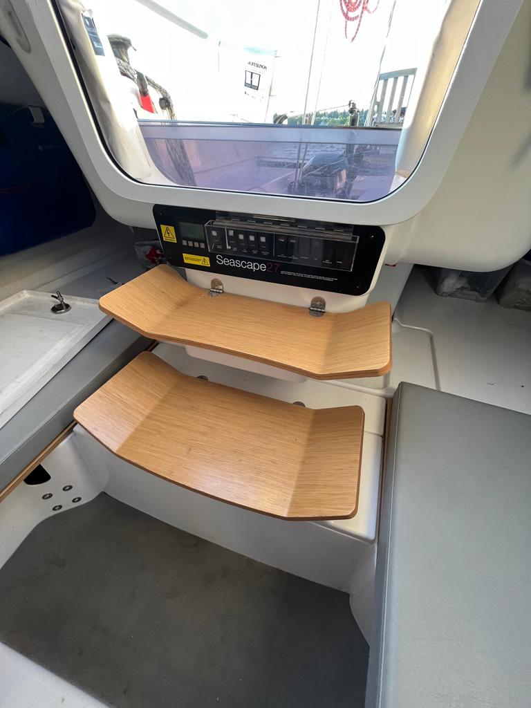 Interior of a 2018 Seascape 27 sailboat with wooden steps and control panel.