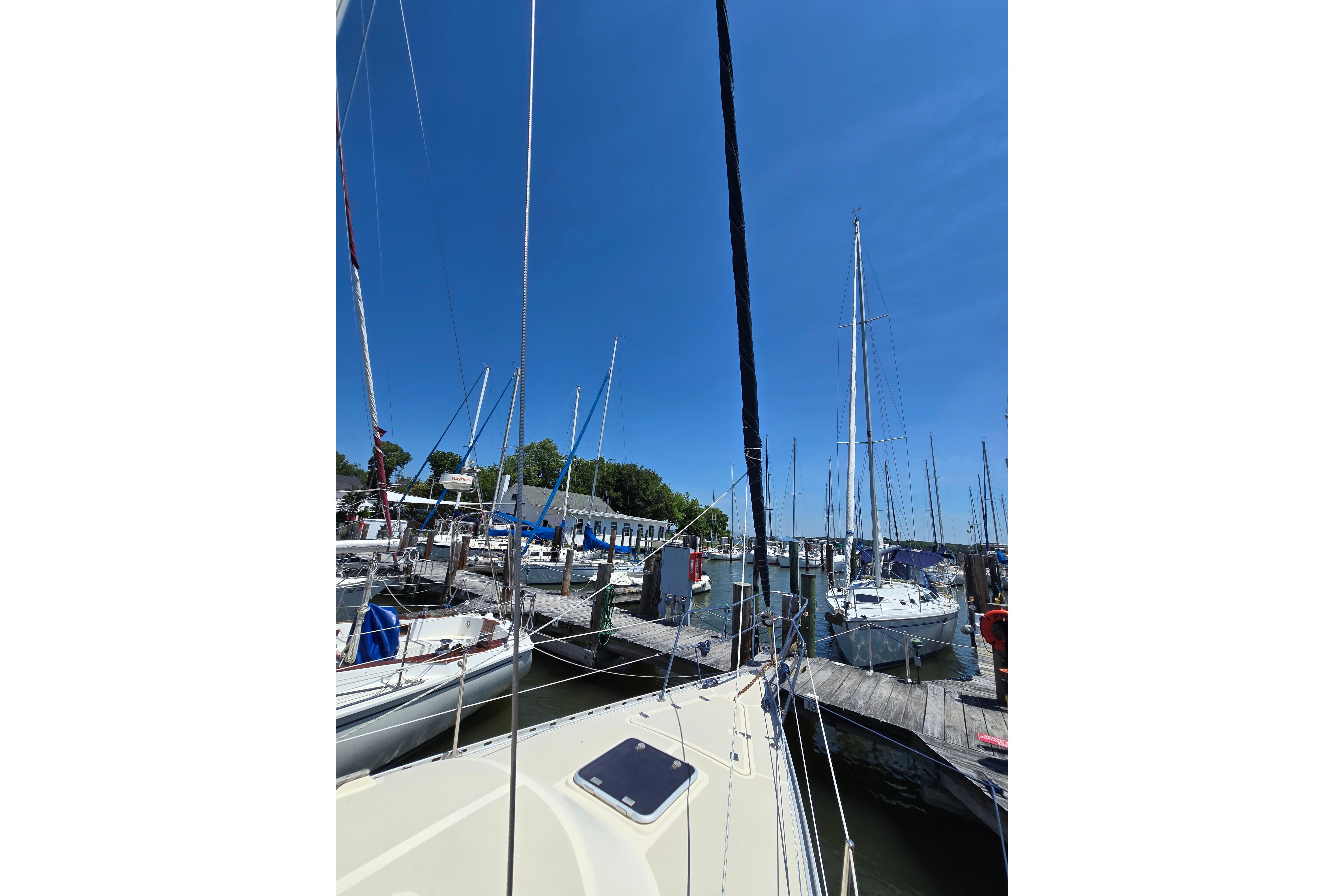 Sailboats docked at a marina under a clear blue sky, featuring a 1993 Caliber 35.