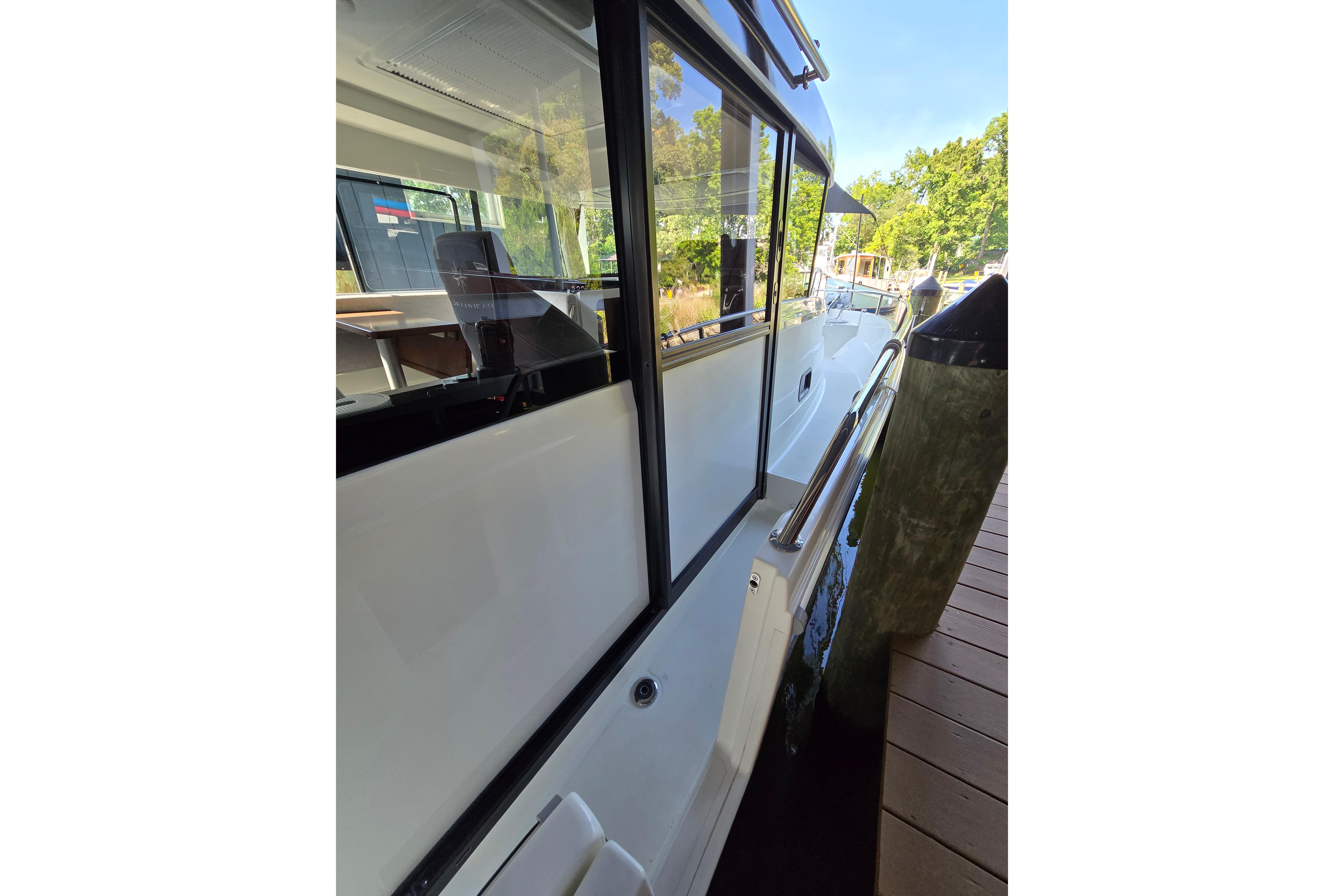 Side view of a Jeanneau NC Sport 895 boat at the dock, featuring large windows and modern design.