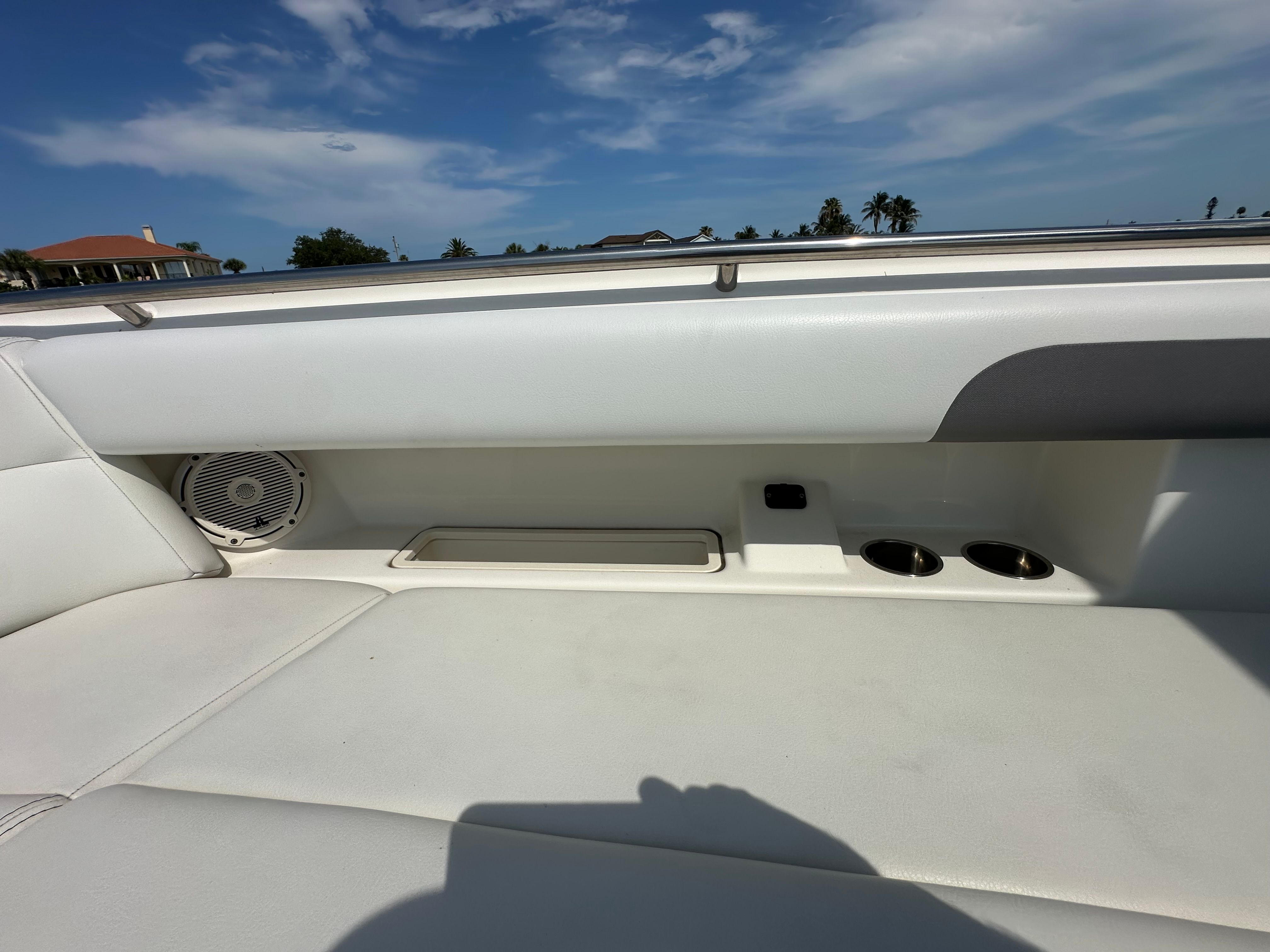 The image shows a boat's white seating area with cup holders and a speaker.