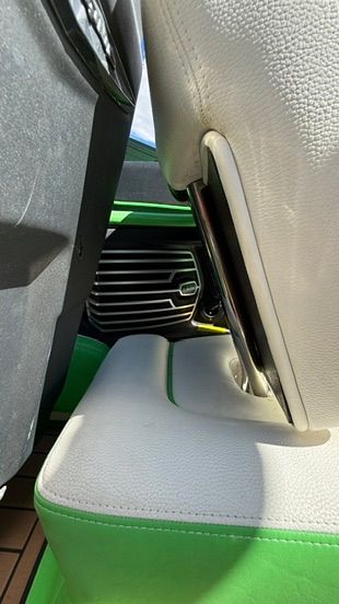 Close-up of a boat interior with white and green seats and a speaker.