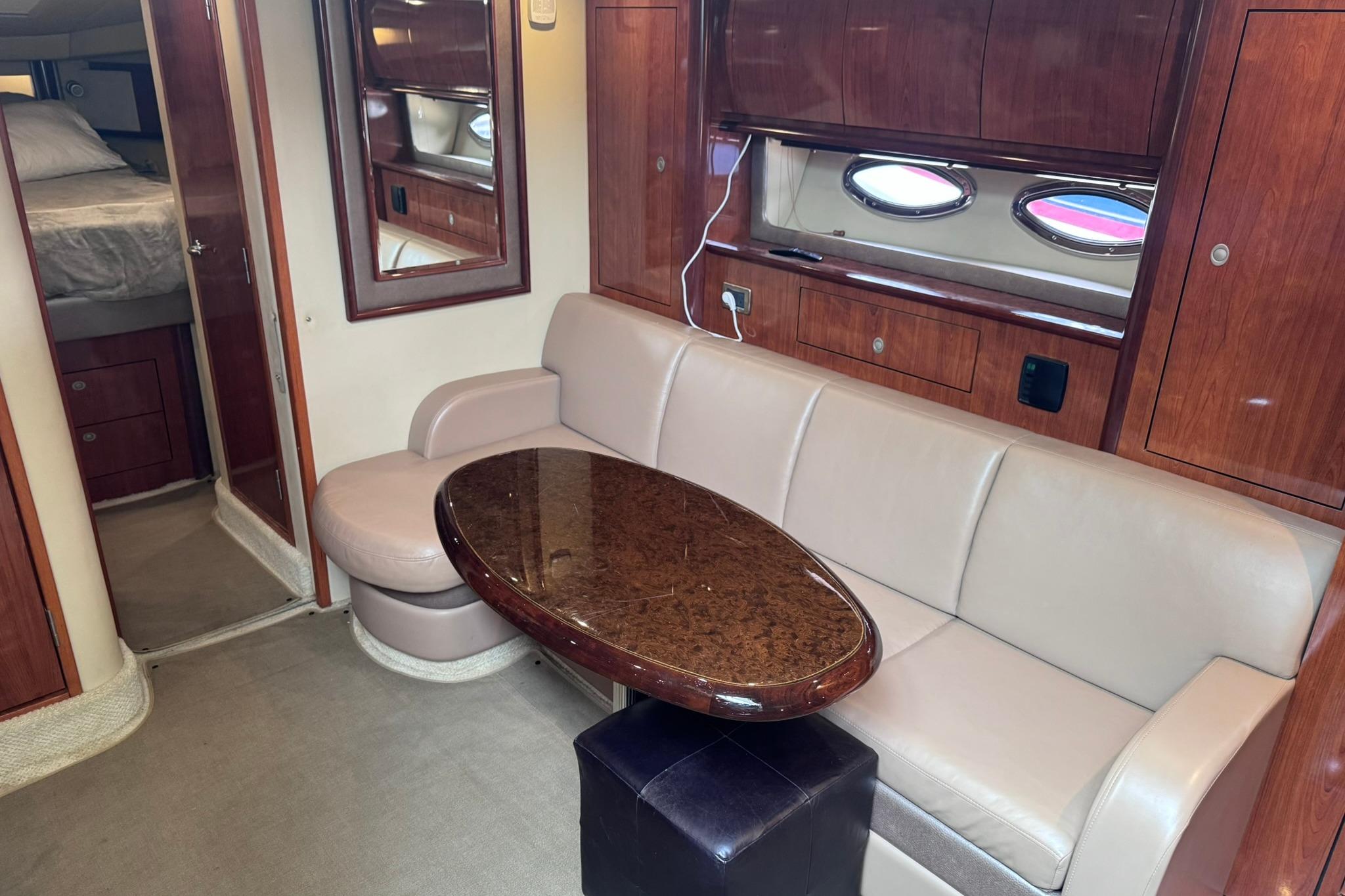Interior of 2004 Sea Ray 390 Sundancer yacht with beige seating and wooden table.