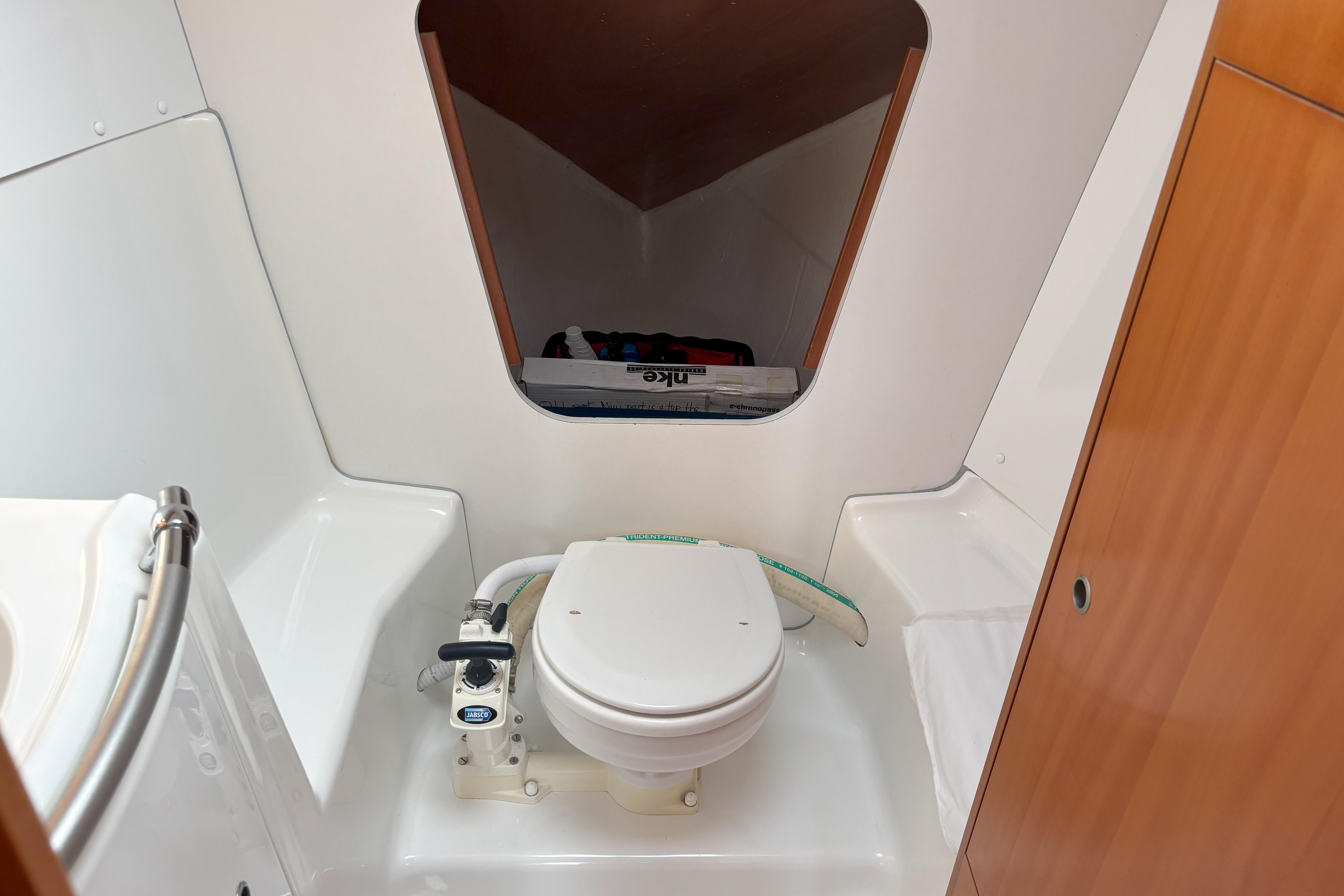 2008 Beneteau First 10R yacht bathroom with compact marine toilet and storage space.
