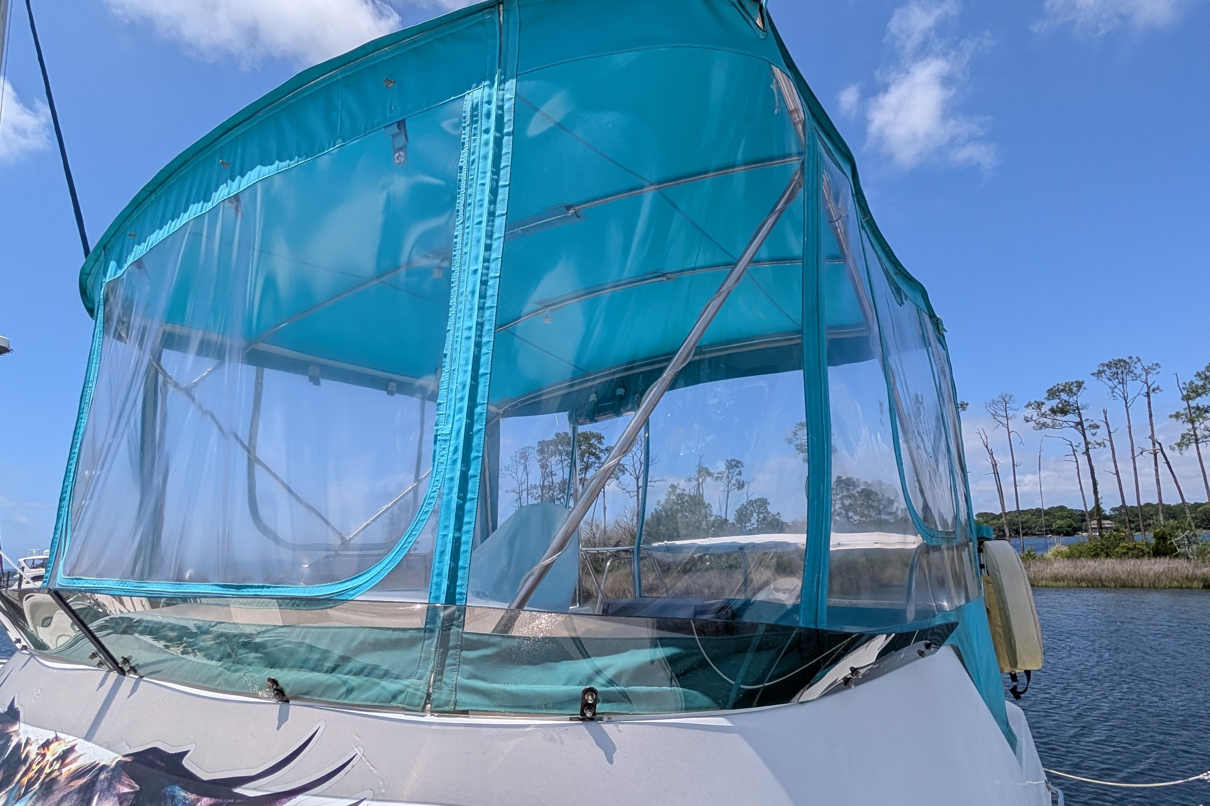 2004 PDQ 34 Powercat with turquoise canopy on a sunny day by the water.