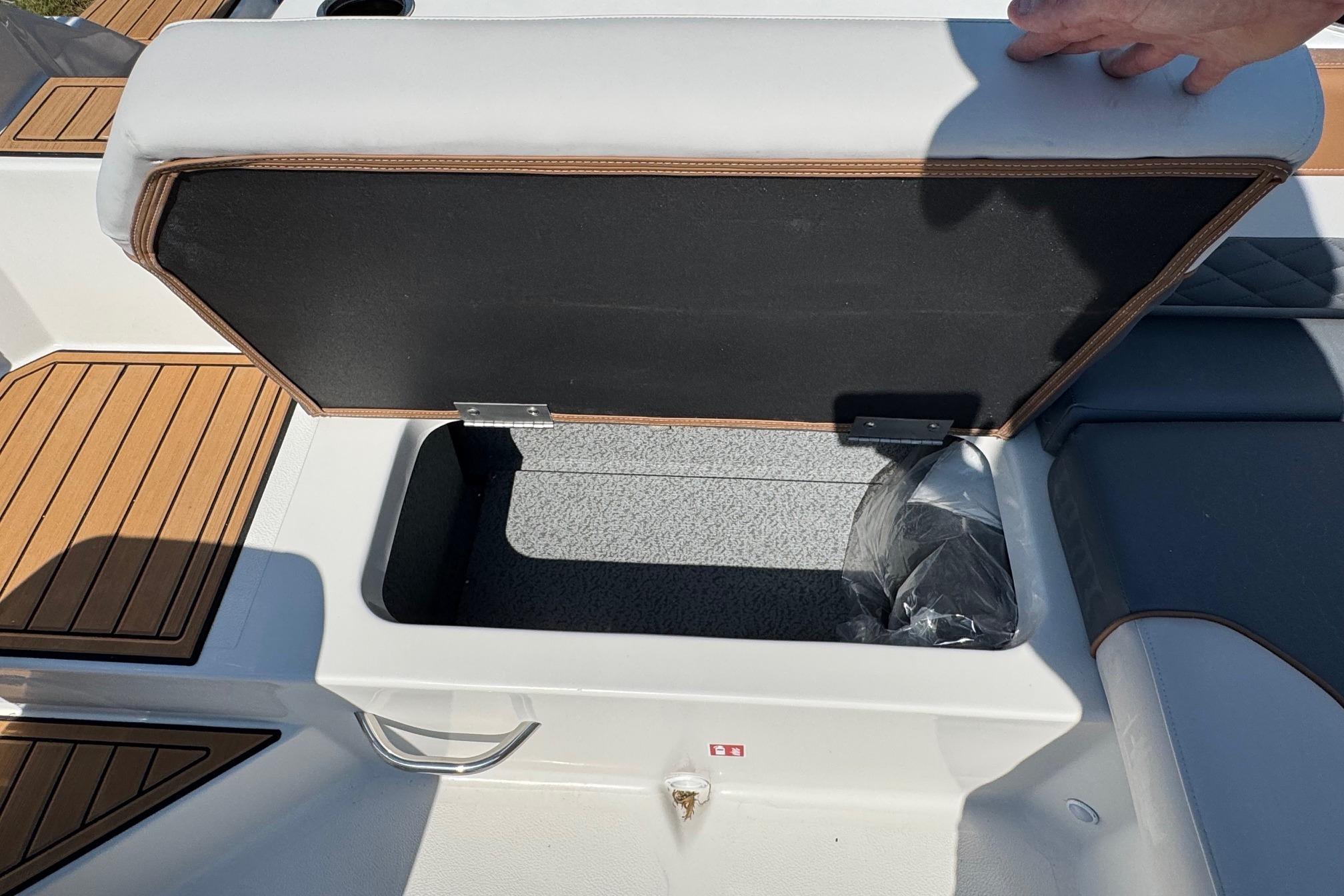 Open storage compartment on 2026 Starcraft SVX 190 OB boat, featuring cushioned seating and wood accents.