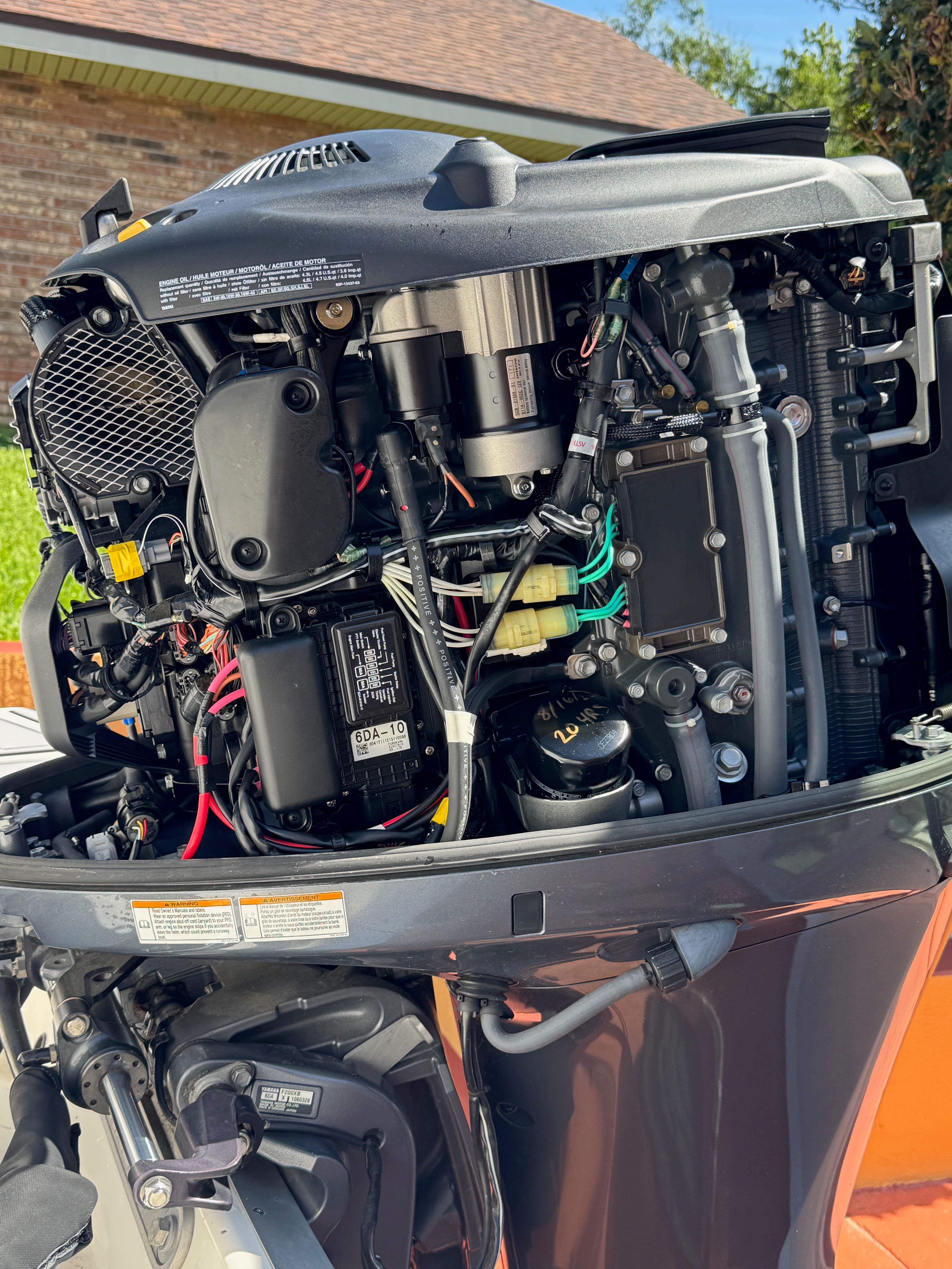 An open outboard motor reveals wiring and mechanical components.