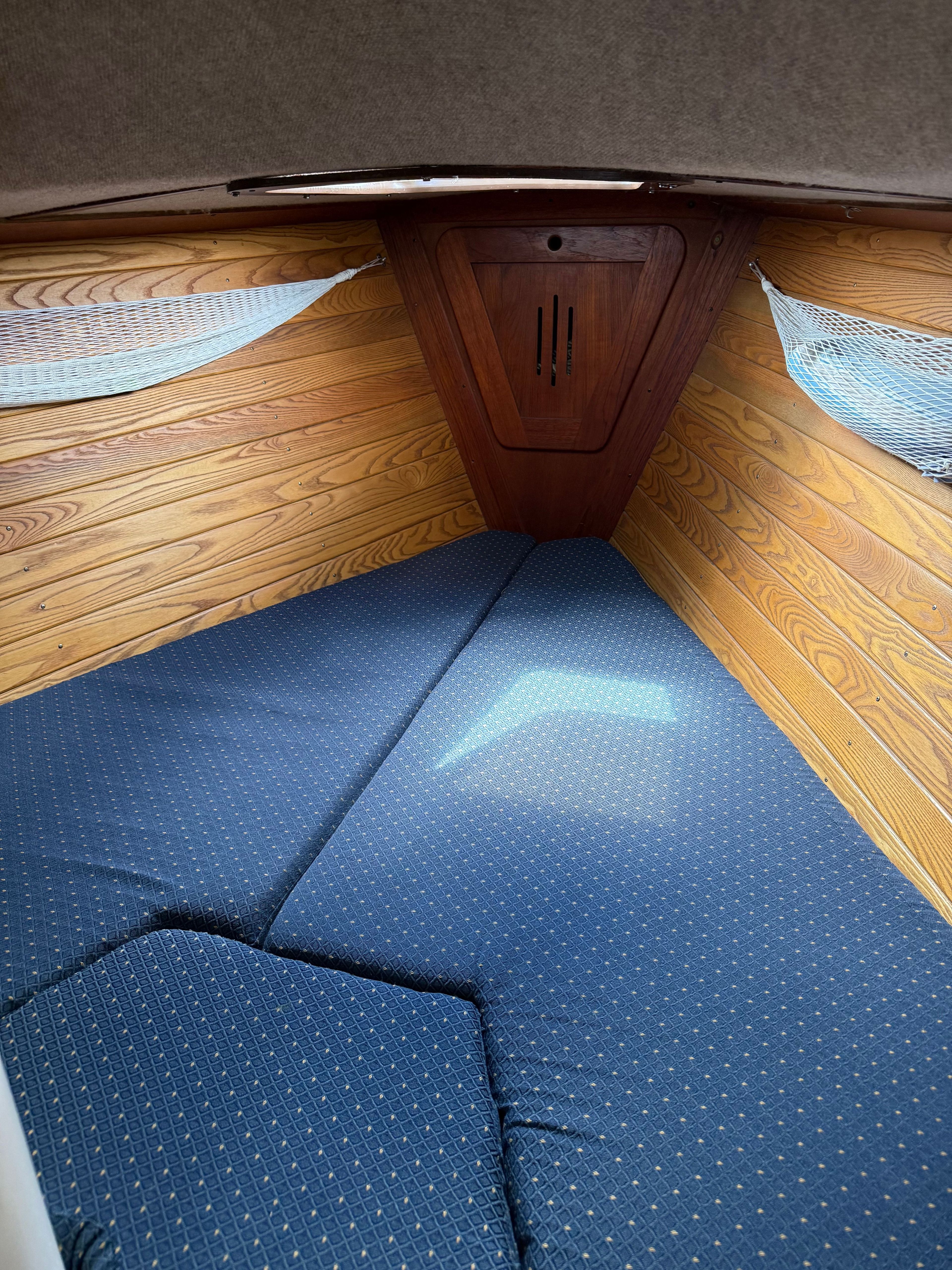 Interior of a sailboat with blue cushions and wooden walls.