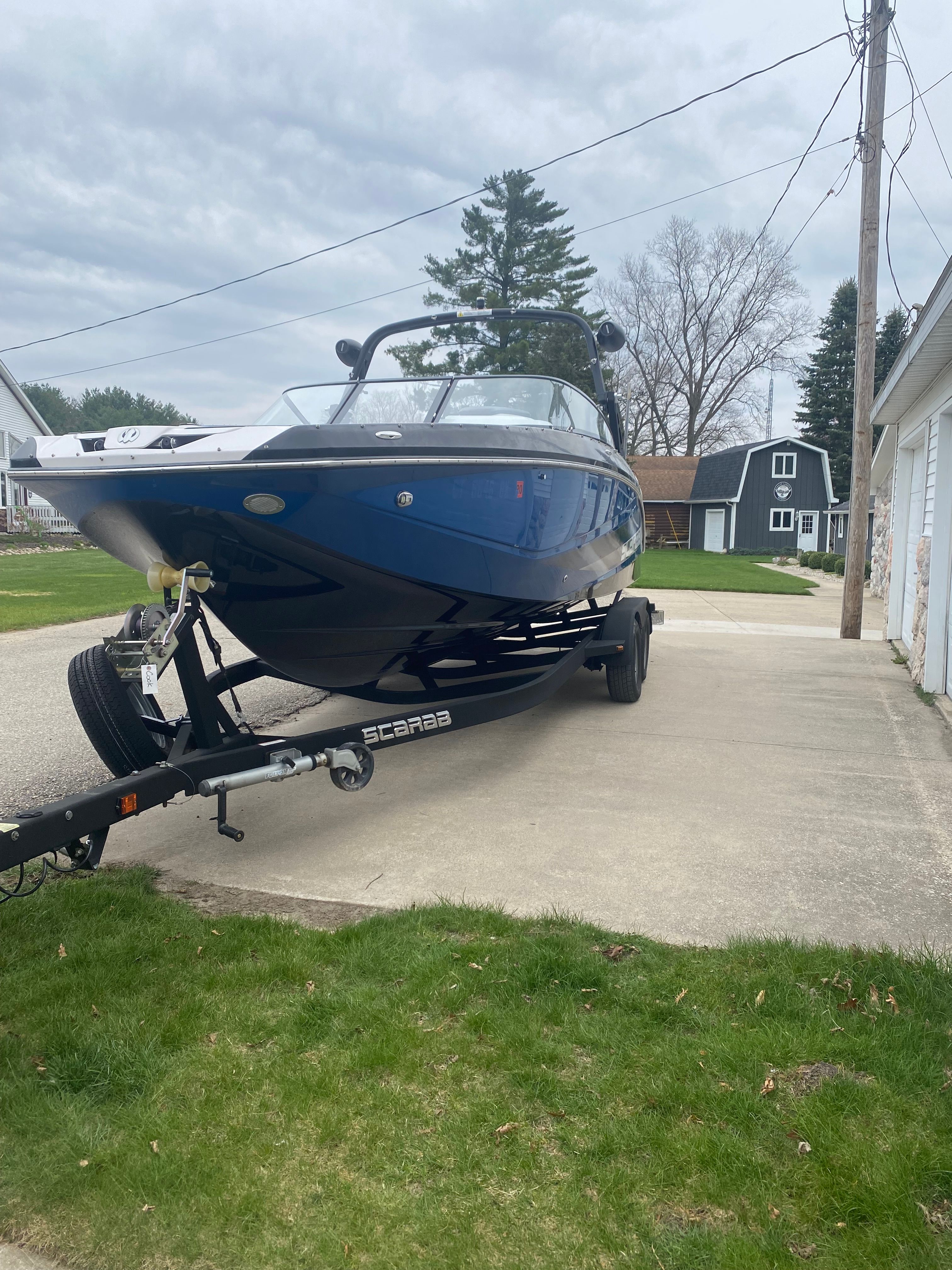 A blue 2018 Scarab 255 HOI on a trailer in a driveway.