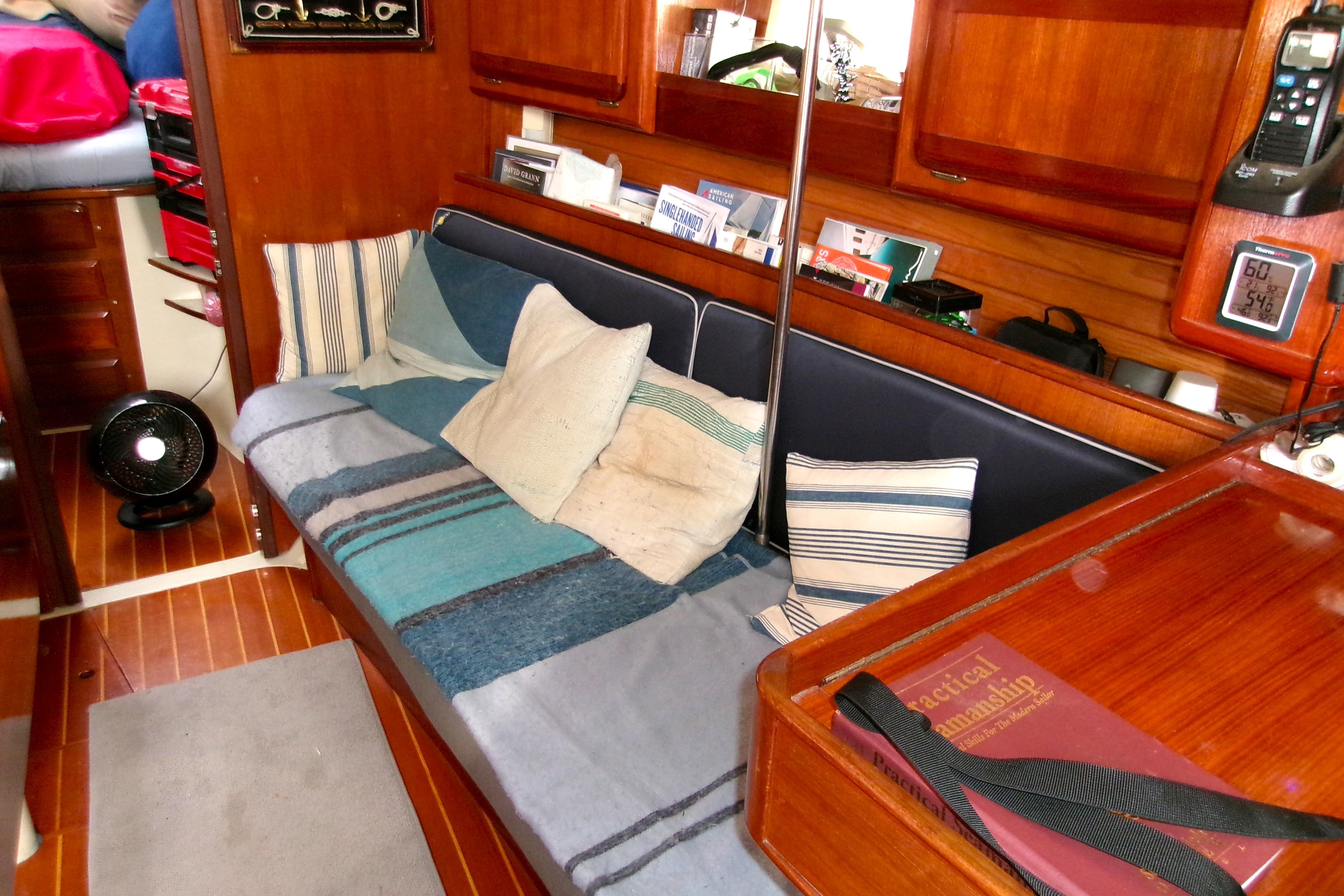 Cozy interior of 1994 Hunter Legend 40 sailboat with cushions and wooden cabinetry.
