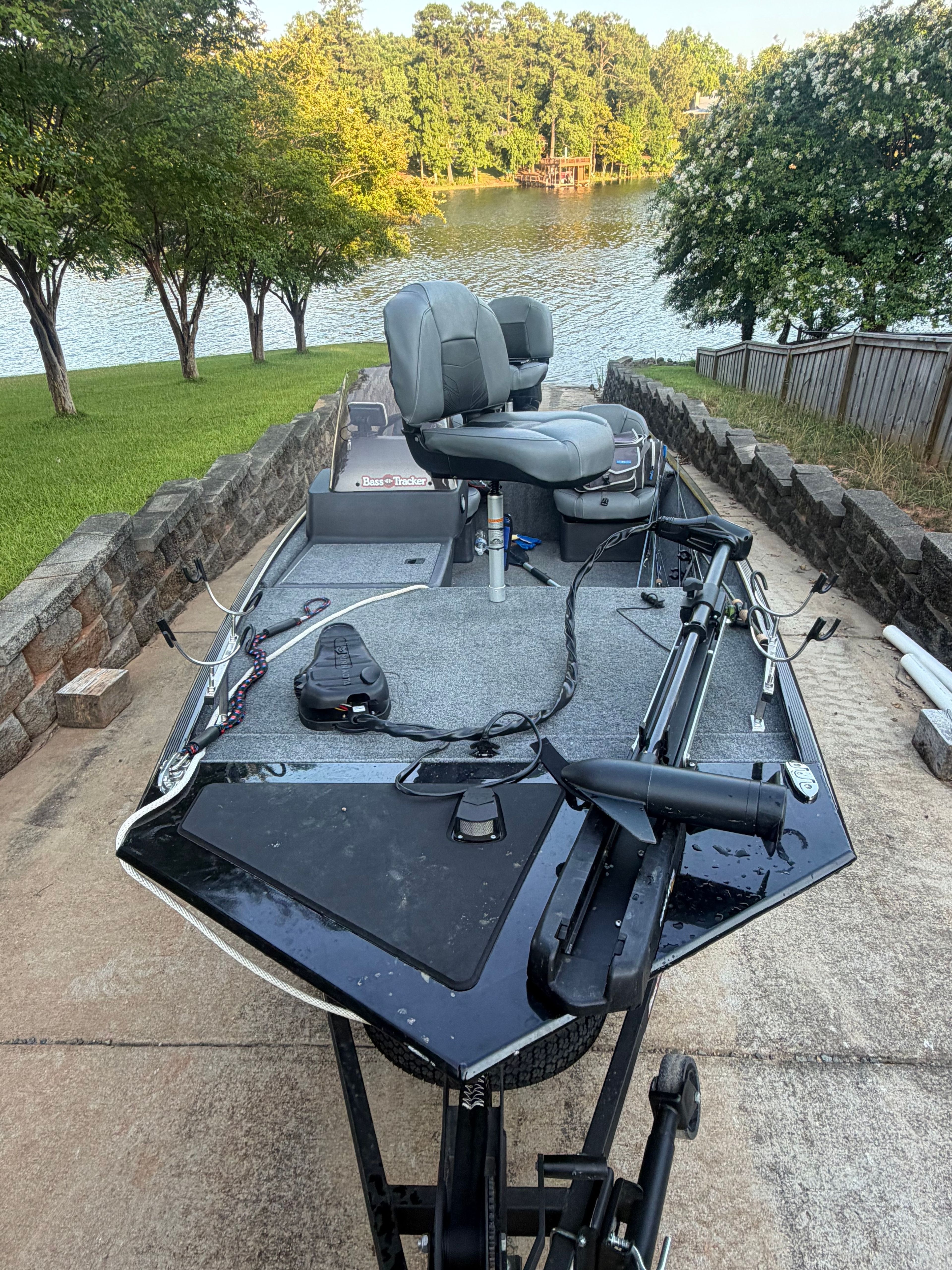 A 2023 Bass Tracker Classic XL boat on a trailer, featuring two seats and a motor, positioned on a ramp by a lake.