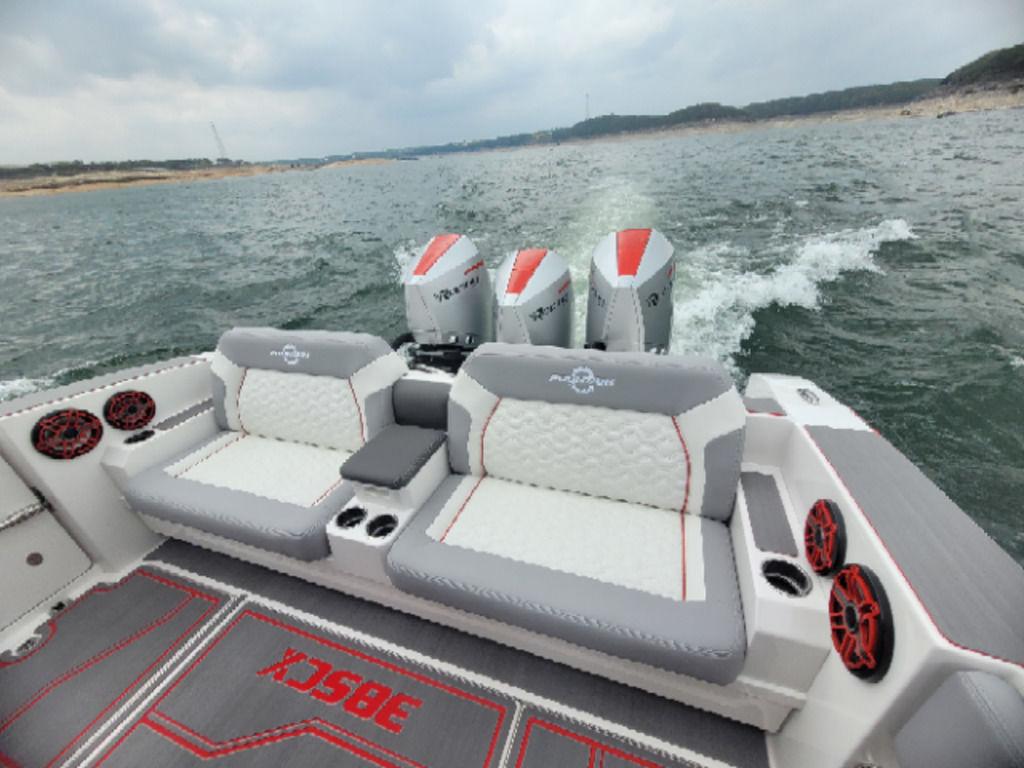2024 Fountain 38 SCX boat interior with seating and triple outboard engines on water.