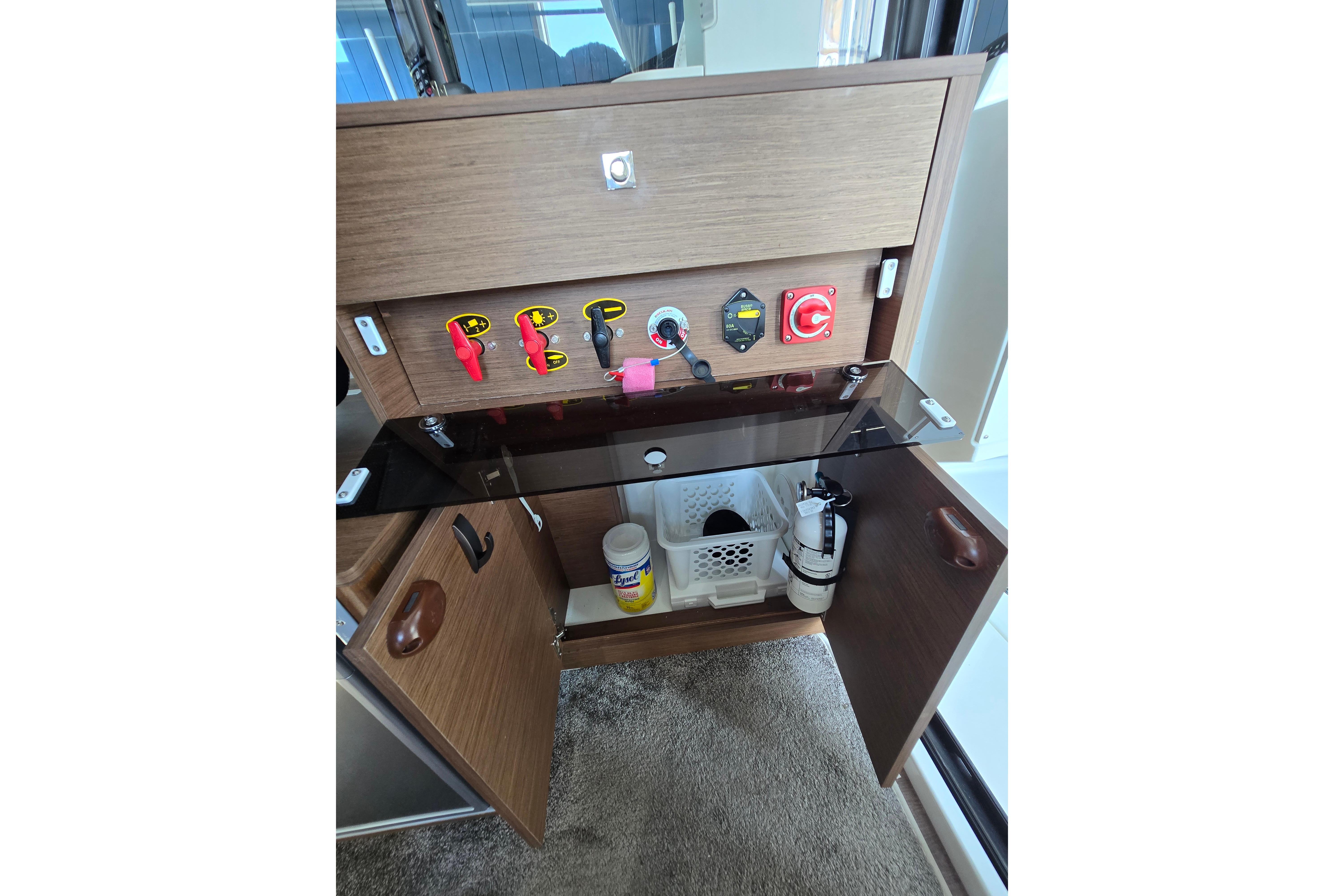 Electrical panel on a boat with switches and storage below.