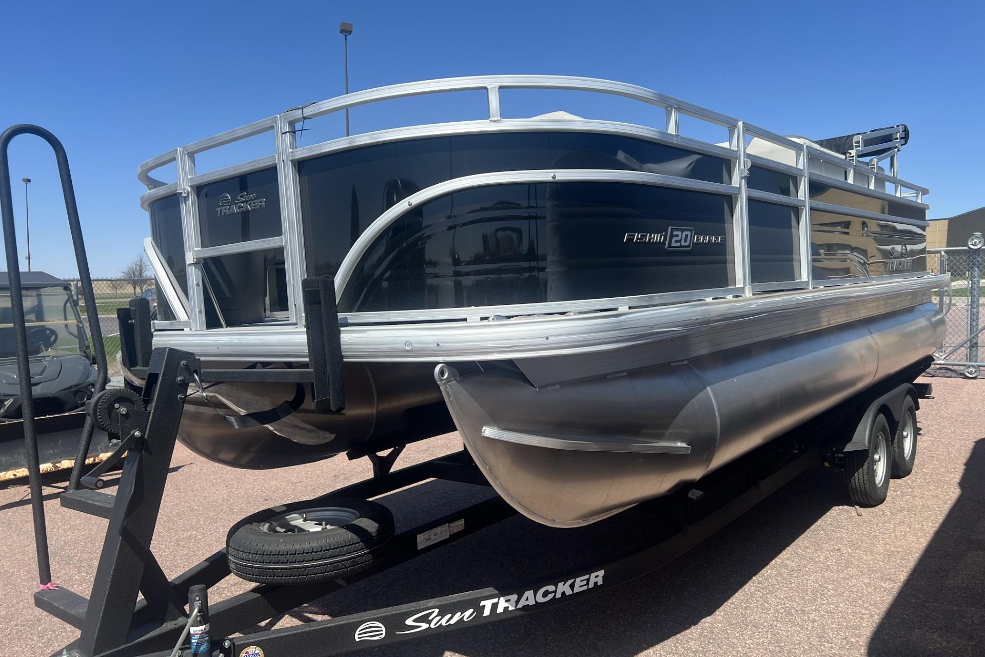 2026 Sun Tracker Fishin' Barge 20 DLX pontoon boat on trailer, parked outdoors.