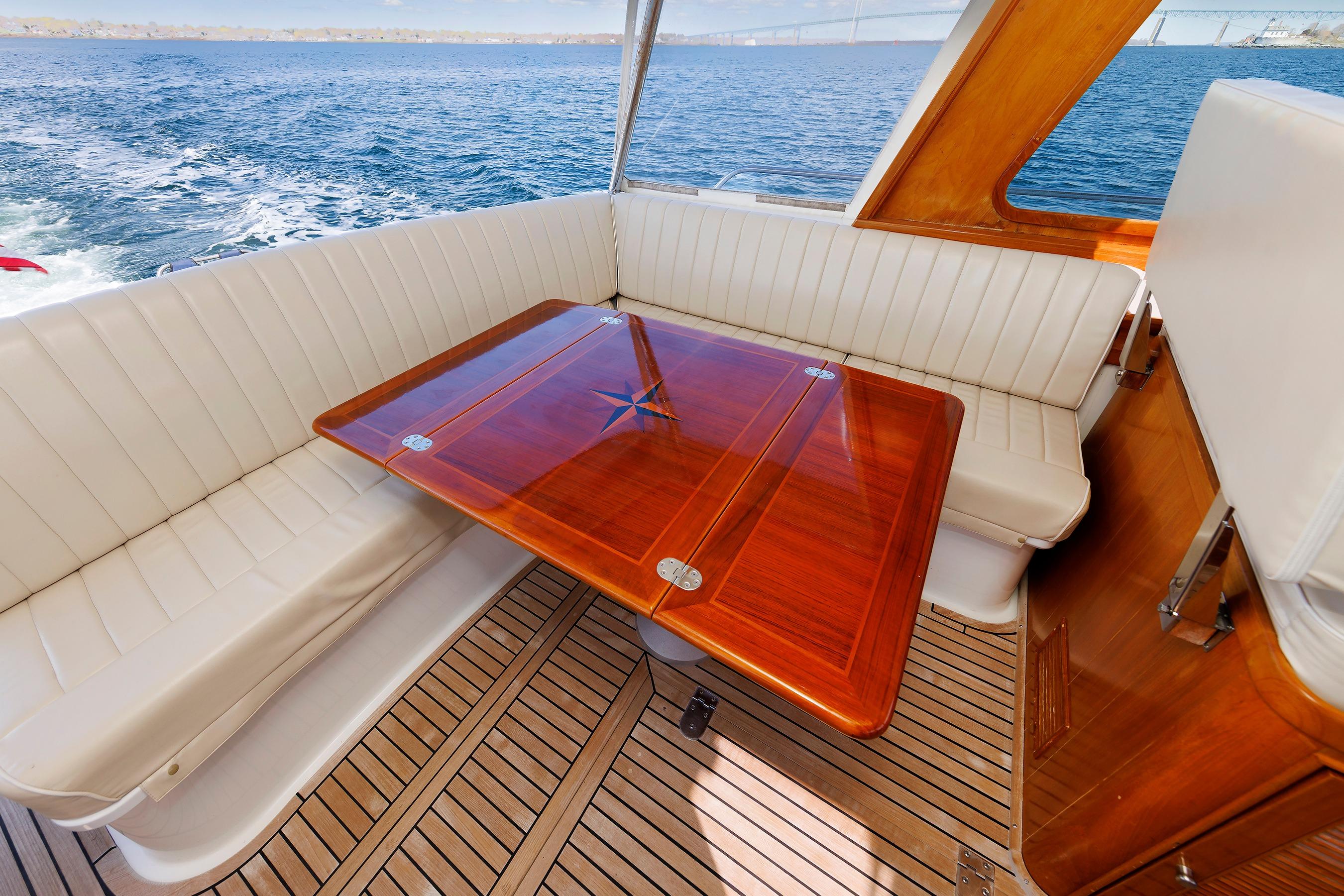 Luxurious Eastbay 49 yacht interior with elegant wood table and white seating, 2000 model.