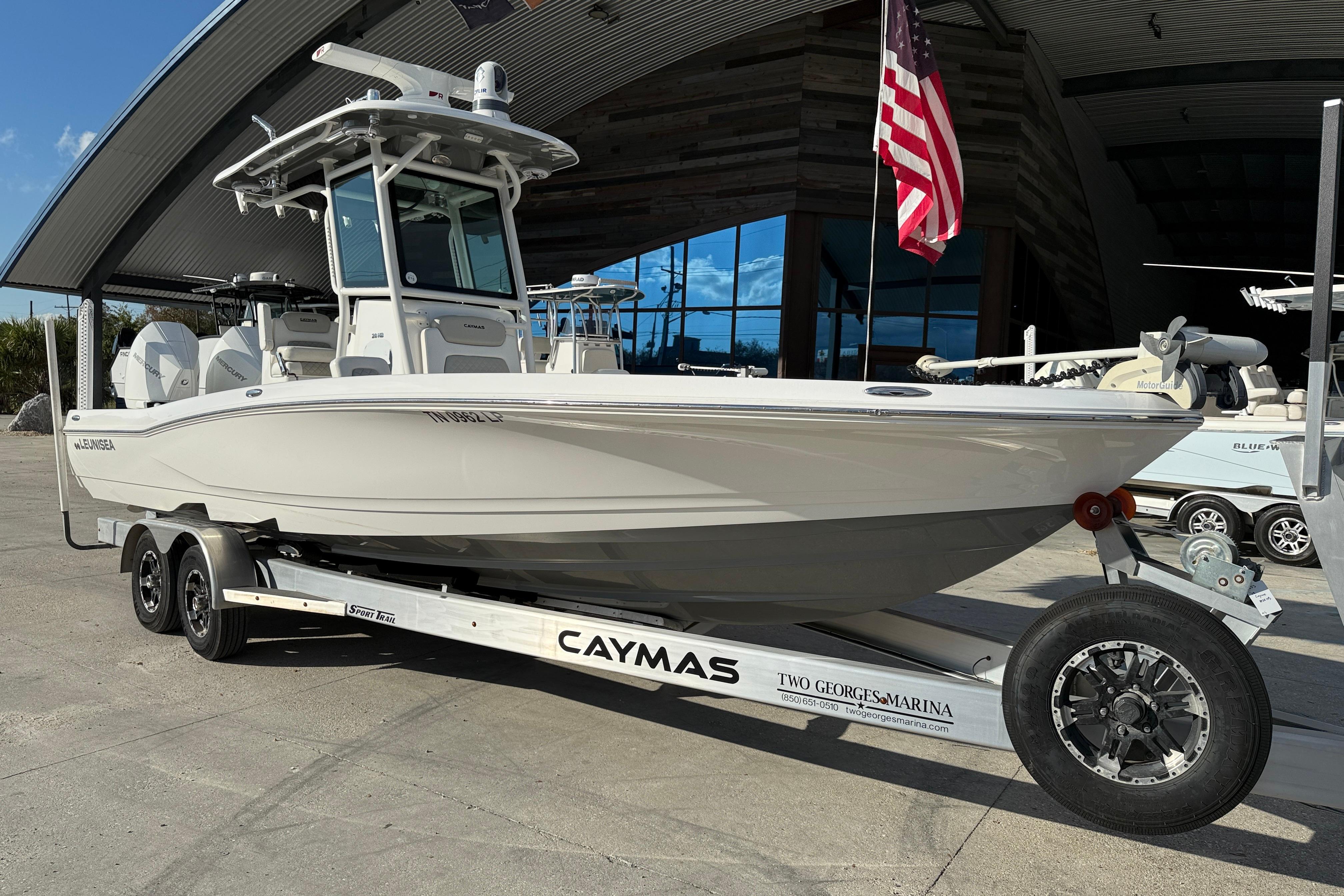 2022 Caymas 28 HB Twin boat on trailer, displayed outdoors with American flag.