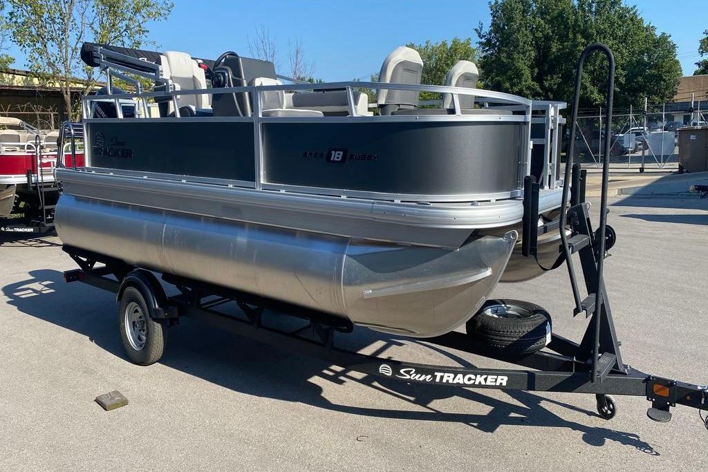 2026 Sun Tracker Bass Buggy 18 DLX pontoon boat on trailer in outdoor setting.