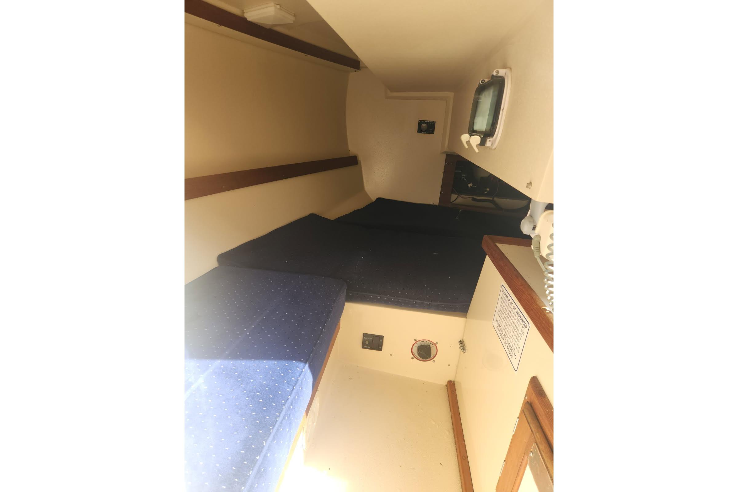 Interior cabin of a 1990 Catalina Capri sailboat with blue cushions and wooden accents.