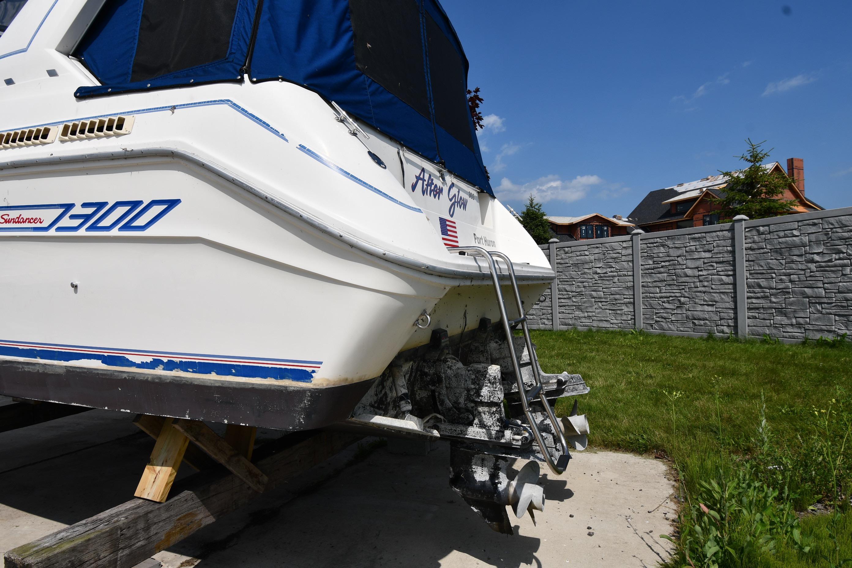 1993 Sea Ray 300 Sundancer boat on land, showing stern and propellers.