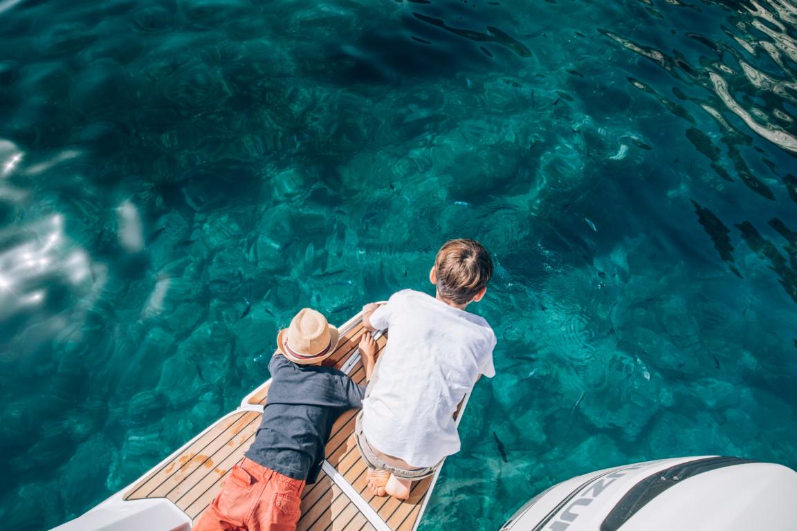 Two people relaxing on a 2024 Beneteau Flyer 10 boat, enjoying clear blue water.