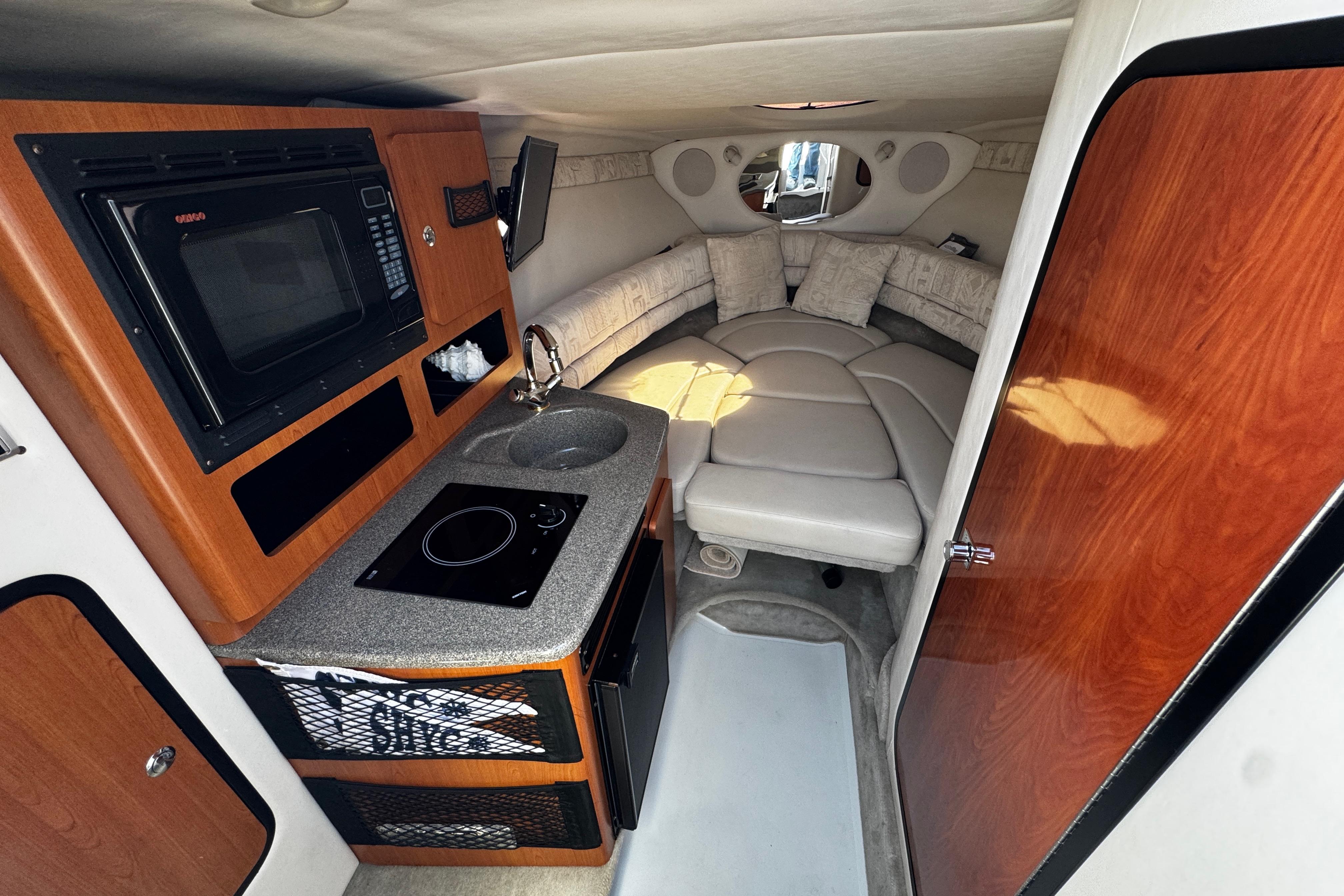 Interior of a 2004 Crownline 250 CR boat with kitchenette and cozy seating area.