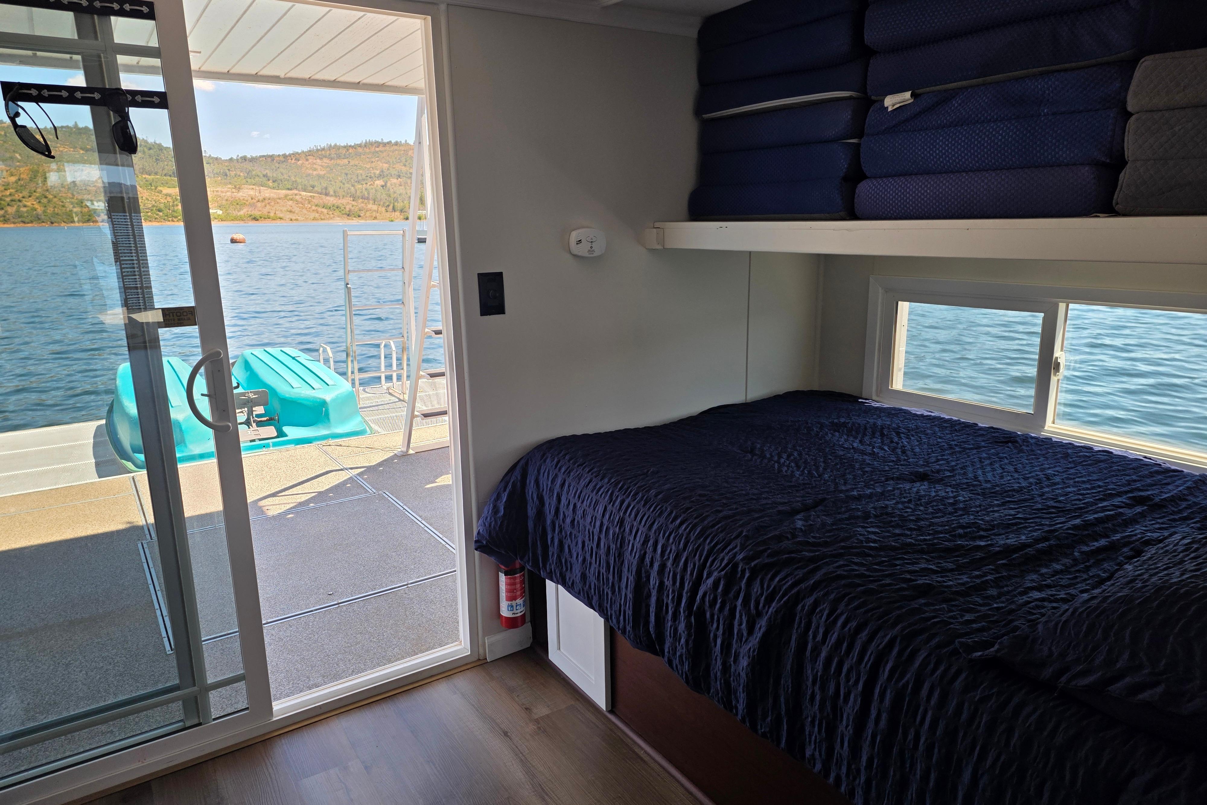 Interior of a 2007 custom houseboat with bed, lake view, and sliding glass door.
