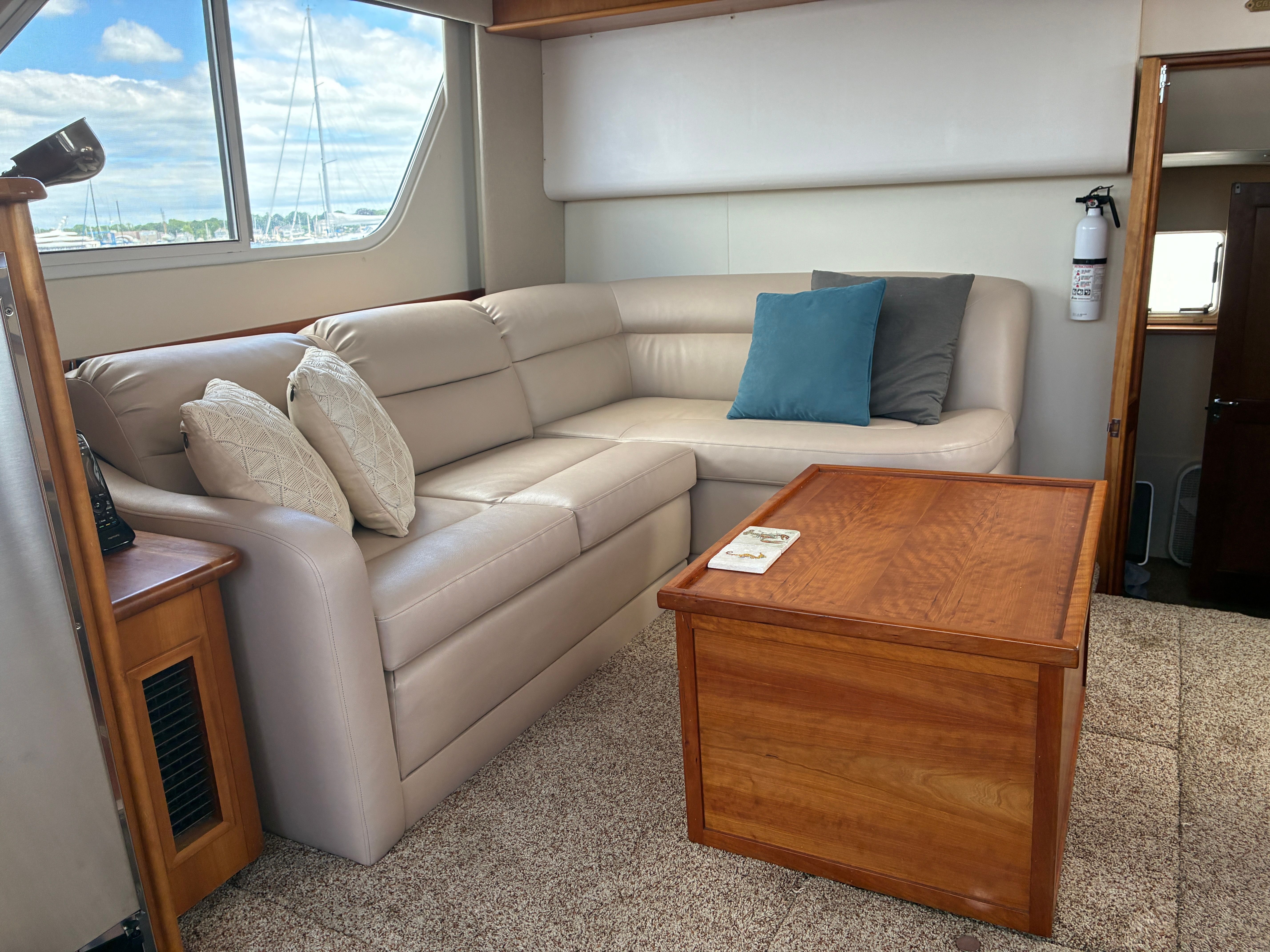 Interior of the 2001 Silverton 392 Motor Yacht with beige sofa and wooden table.