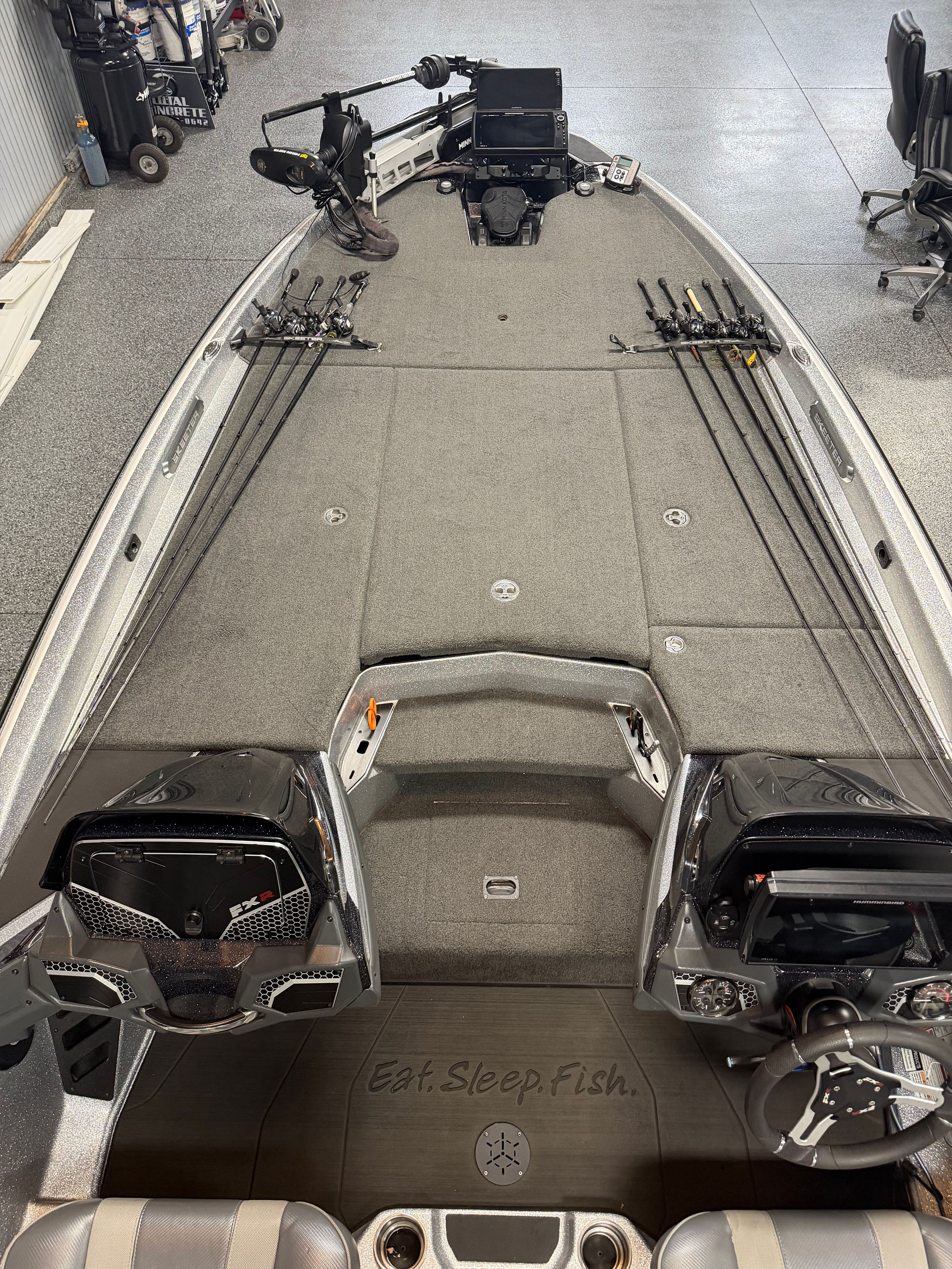 The image shows a modern fishing boat with multiple fishing rods and a steering console.